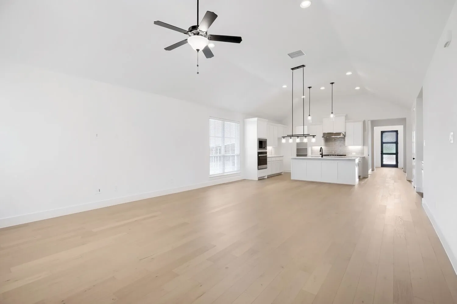 Open-concept living space featuring light wood-finish flooring and a vaulted ceiling