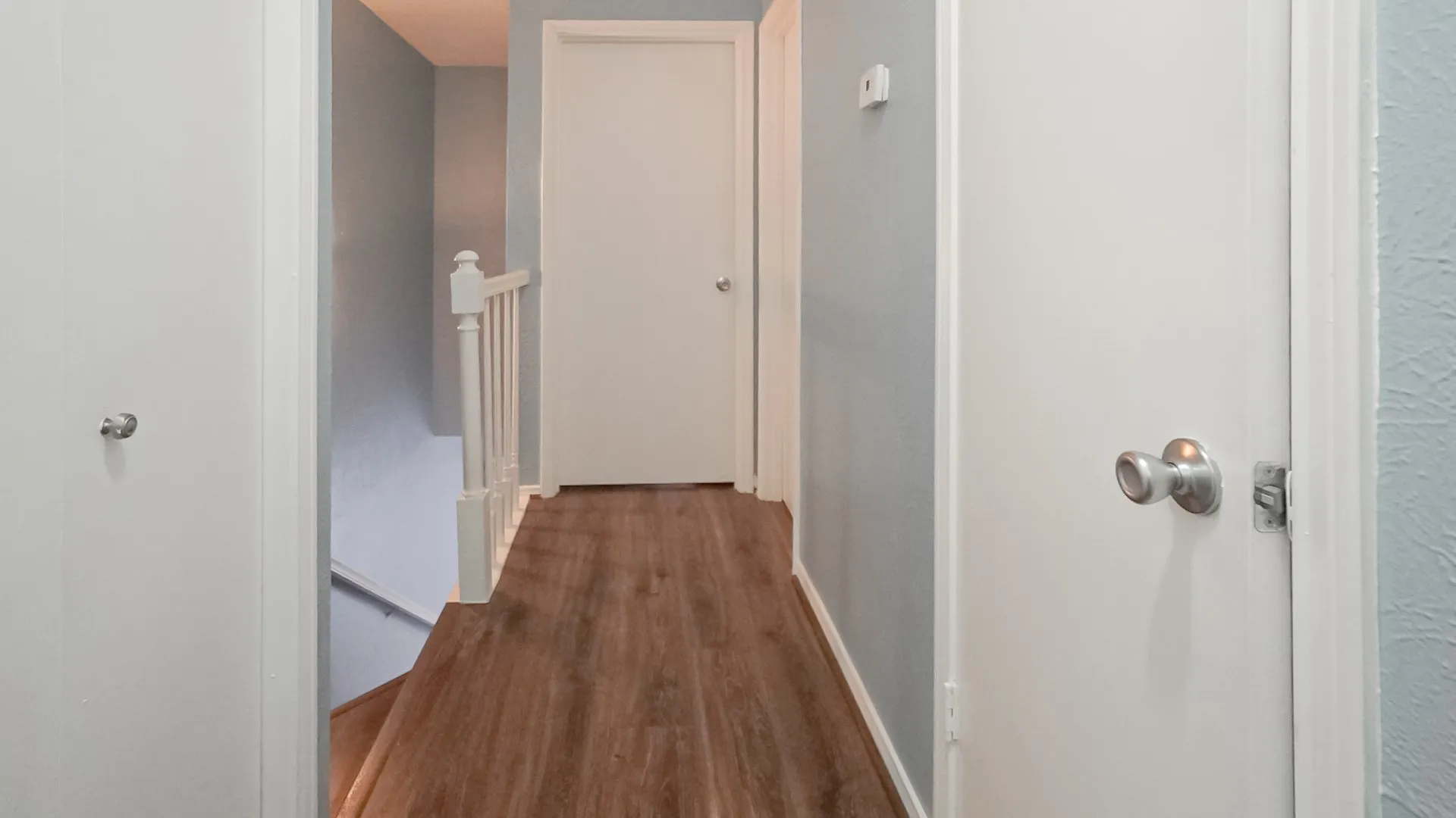 Corridor featuring an upstairs landing and dark wood-style floors
