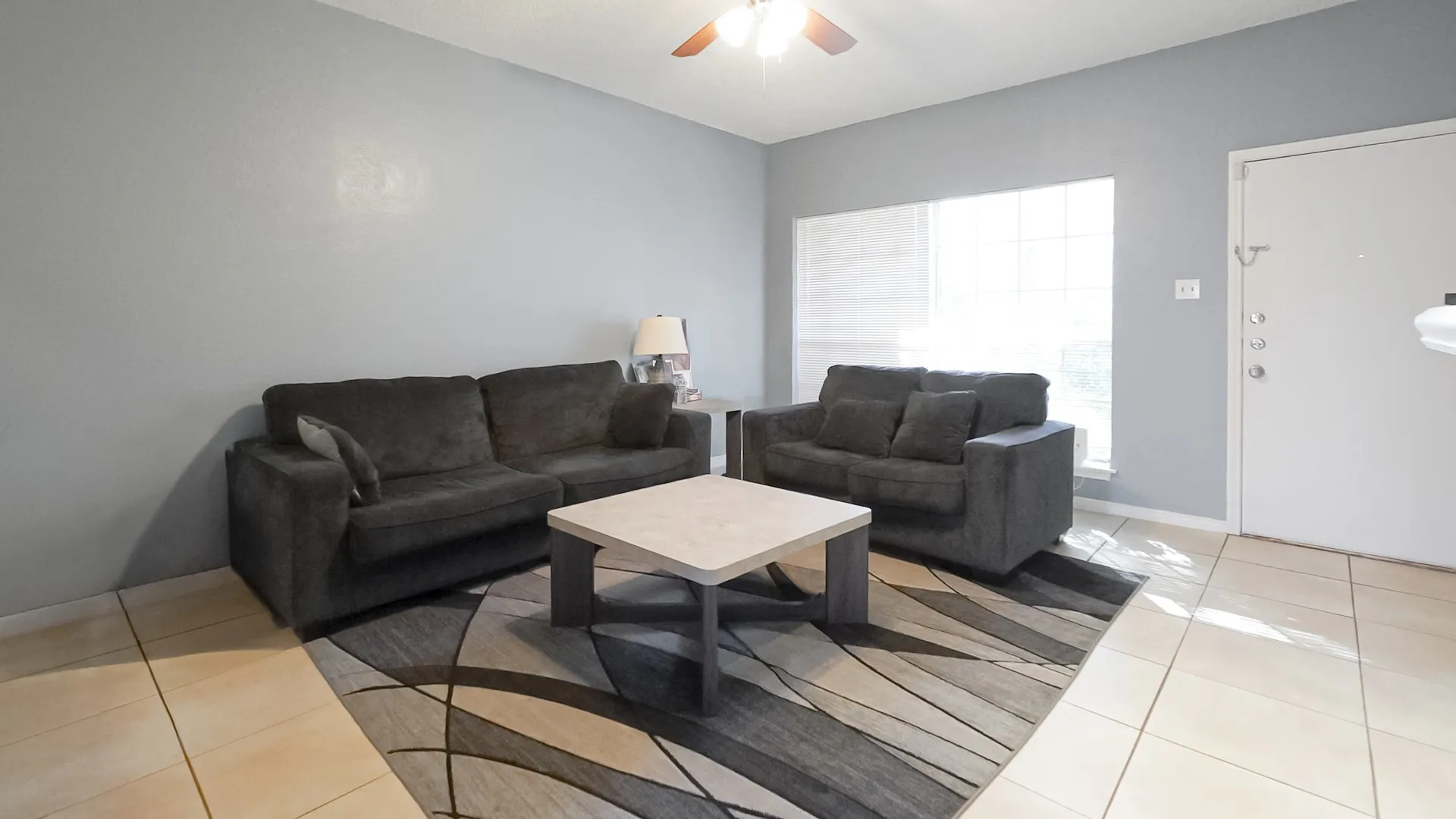 Living area with light tile patterned floors and a ceiling fan