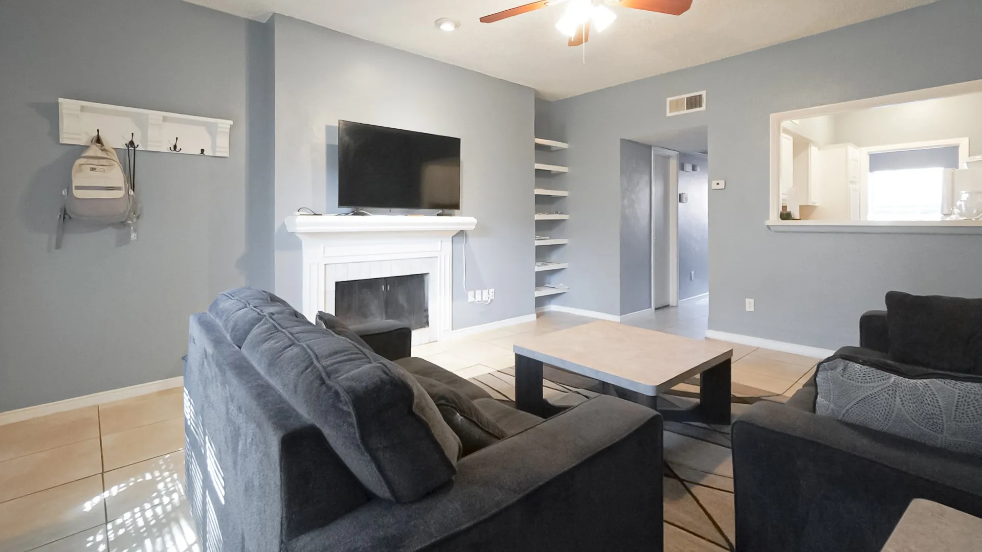 Living room with light tile patterned floors, a fireplace, and a ceiling fan