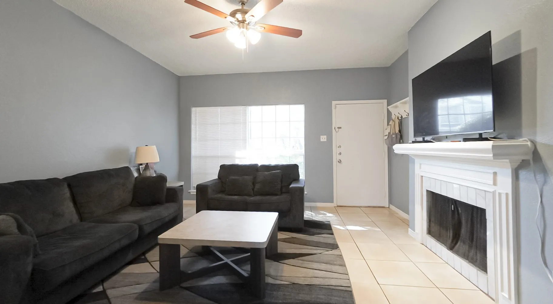 Living room with light tile patterned flooring, a fireplace, and ceiling fan