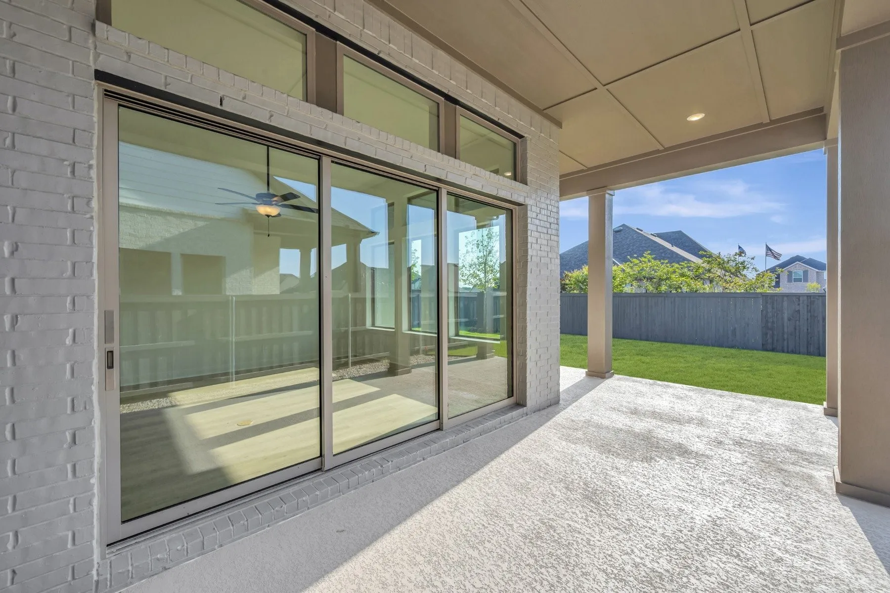 Covered outdoor patio featuring a concrete surface, a brick exterior wall, and a full-height sliding glass door system