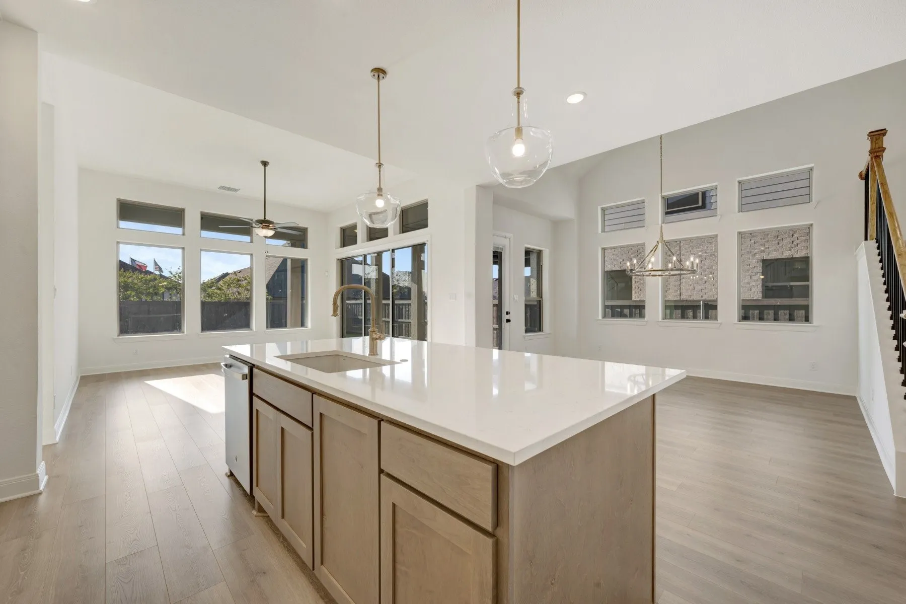 Kitchen island with a light-toned countertop and integrated sink, complemented by pendant lighting and wood-finish flooring