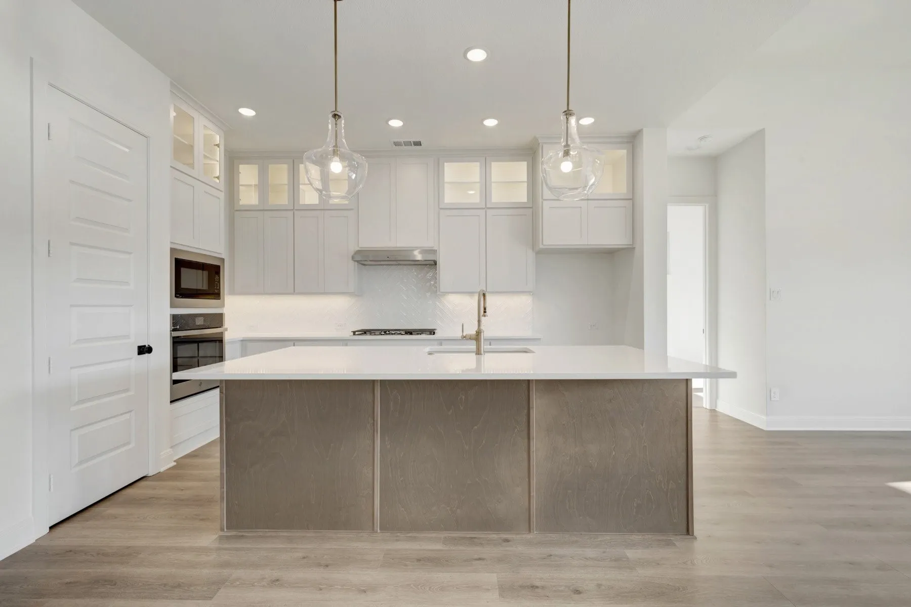 Modern kitchen featuring a central island with a light wood-finish base, white countertop, and gold-finish faucet