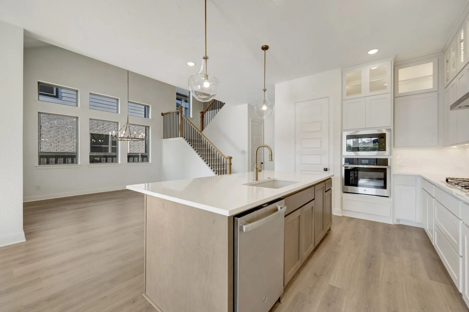 Spacious kitchen island featuring a built-in sink, stainless steel dishwasher, and pendant lighting