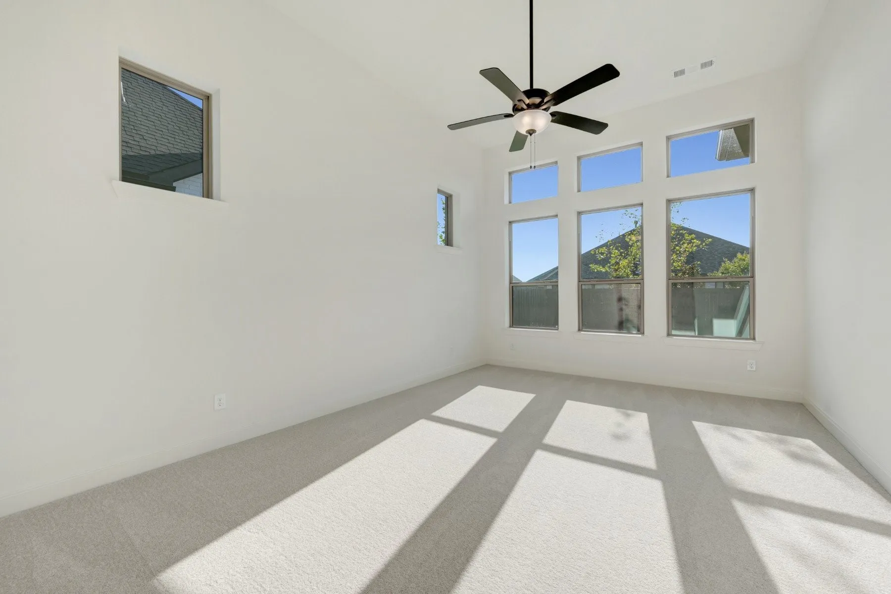 Room with light-colored carpeting, white walls, and a multi-pane window configuration