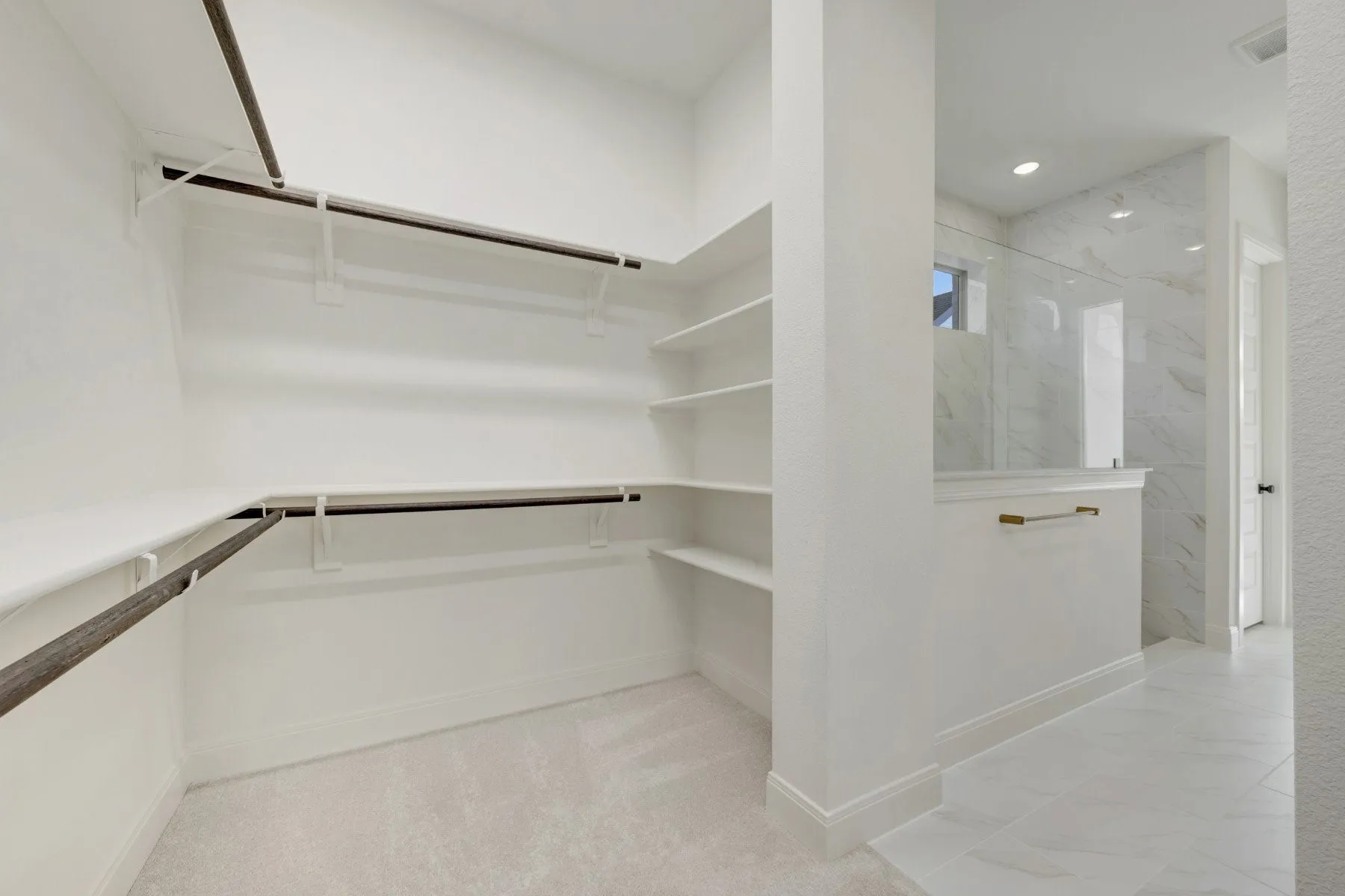 Walk-in closet with carpeted flooring, multiple hanging rods, and built-in shelving