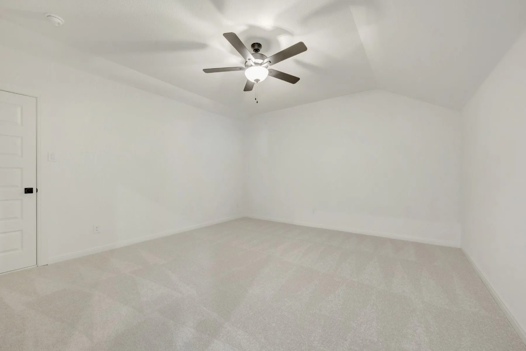 Spacious room featuring vaulted ceilings and light-colored carpeting