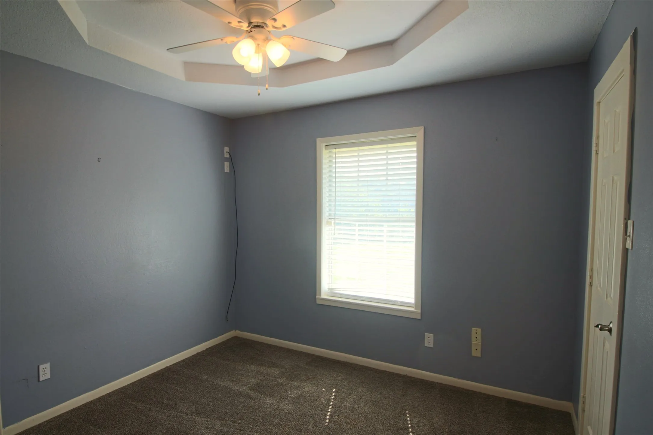 Bedroom with walk in closet, decorative ceiling and ceiling fan.