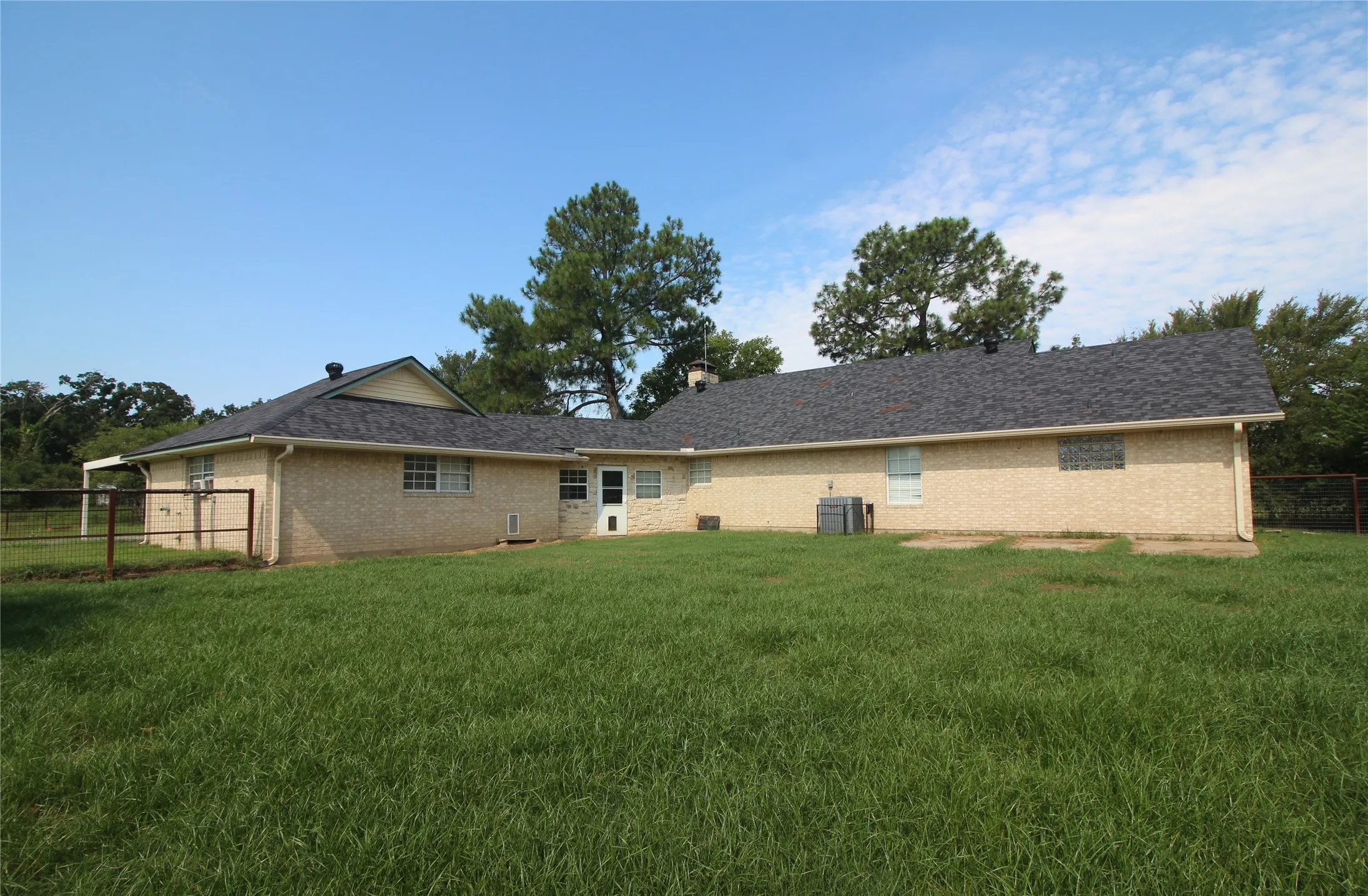 Ranch-style house featuring an attached carport, a front lawn, and a shingled roof