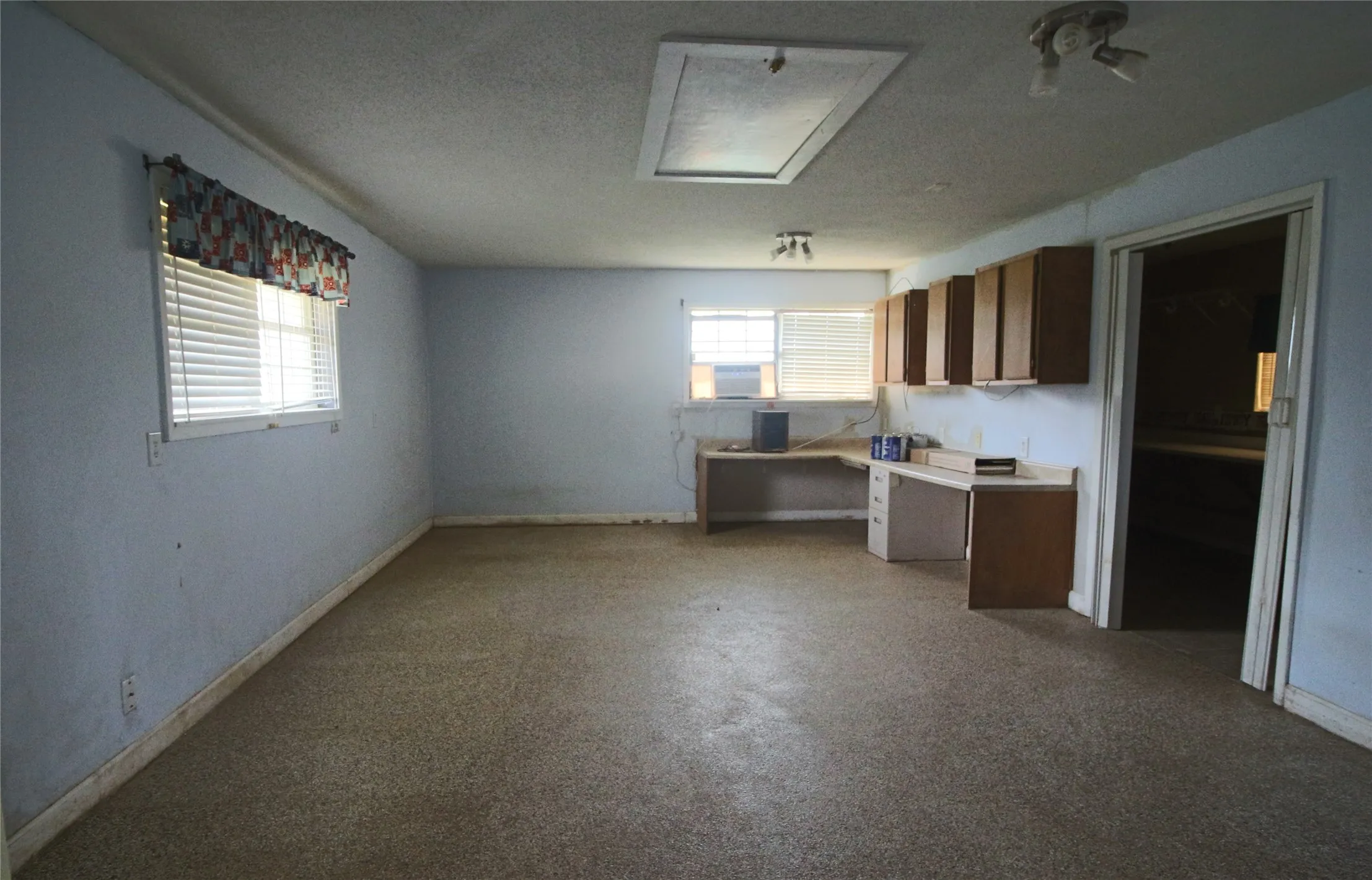 Converted garage area with built in cabinets, window A/C unit and carpet.