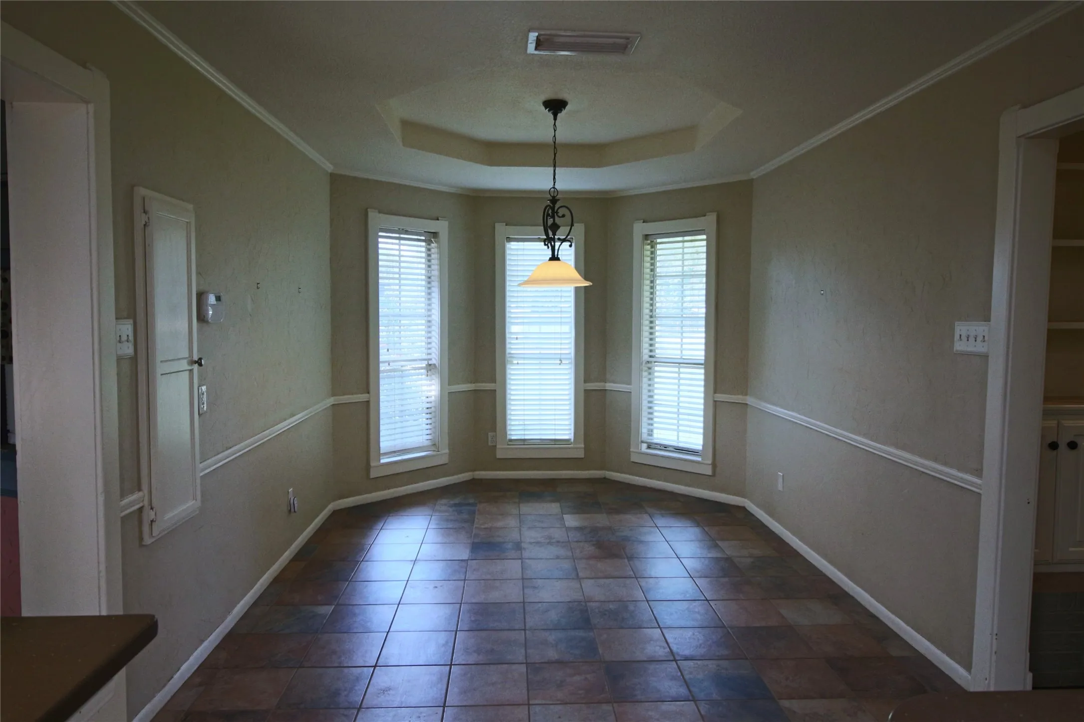 Dining area featuring a raised ceiling, crown molding and wall mounted ironing board.