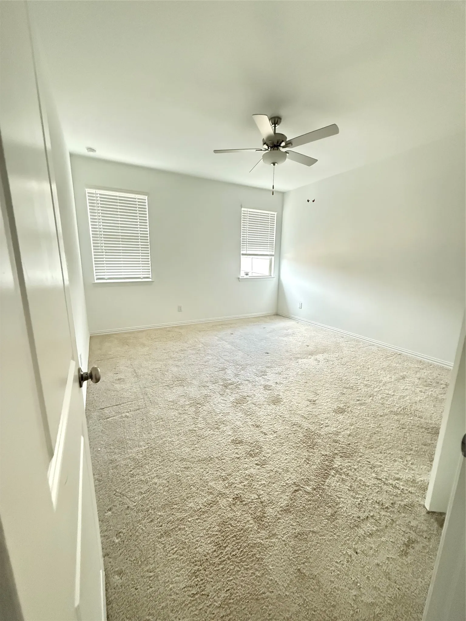 Carpeted spare room featuring baseboards and a ceiling fan