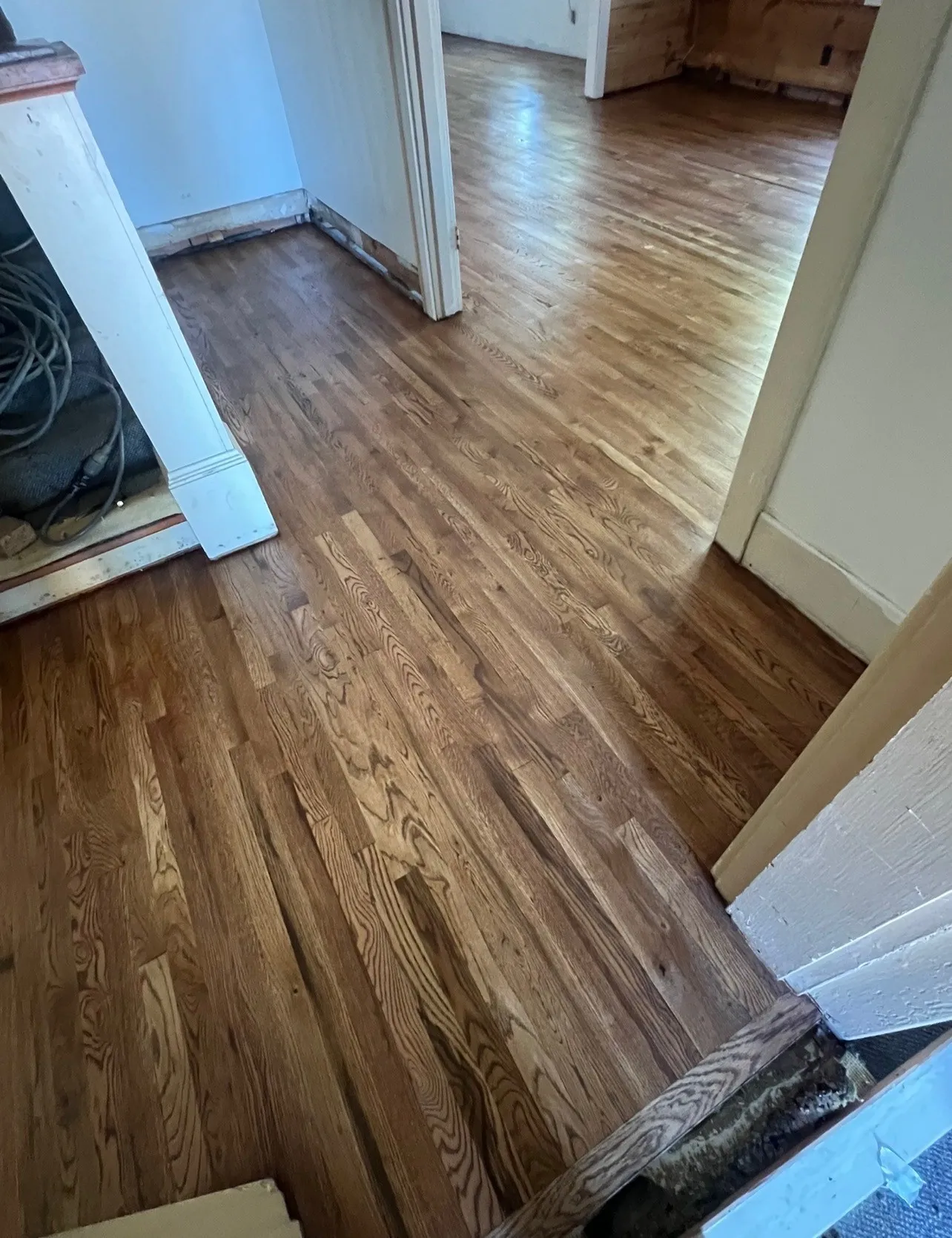 Spacious hallway showcasing rich wood-finish flooring throughout, neutral wall finishes, and multiple doorway openings that define distinct living areas within the home