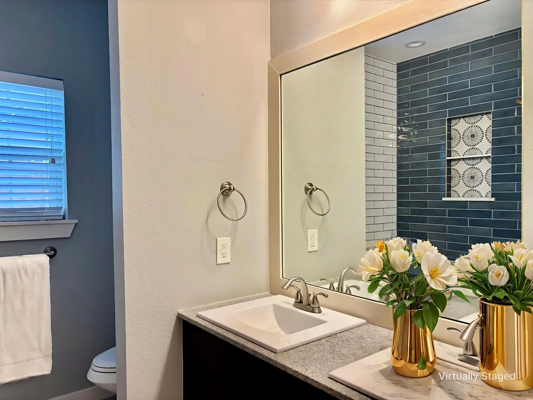 Full bathroom with double vanity, a textured wall, and tiled shower