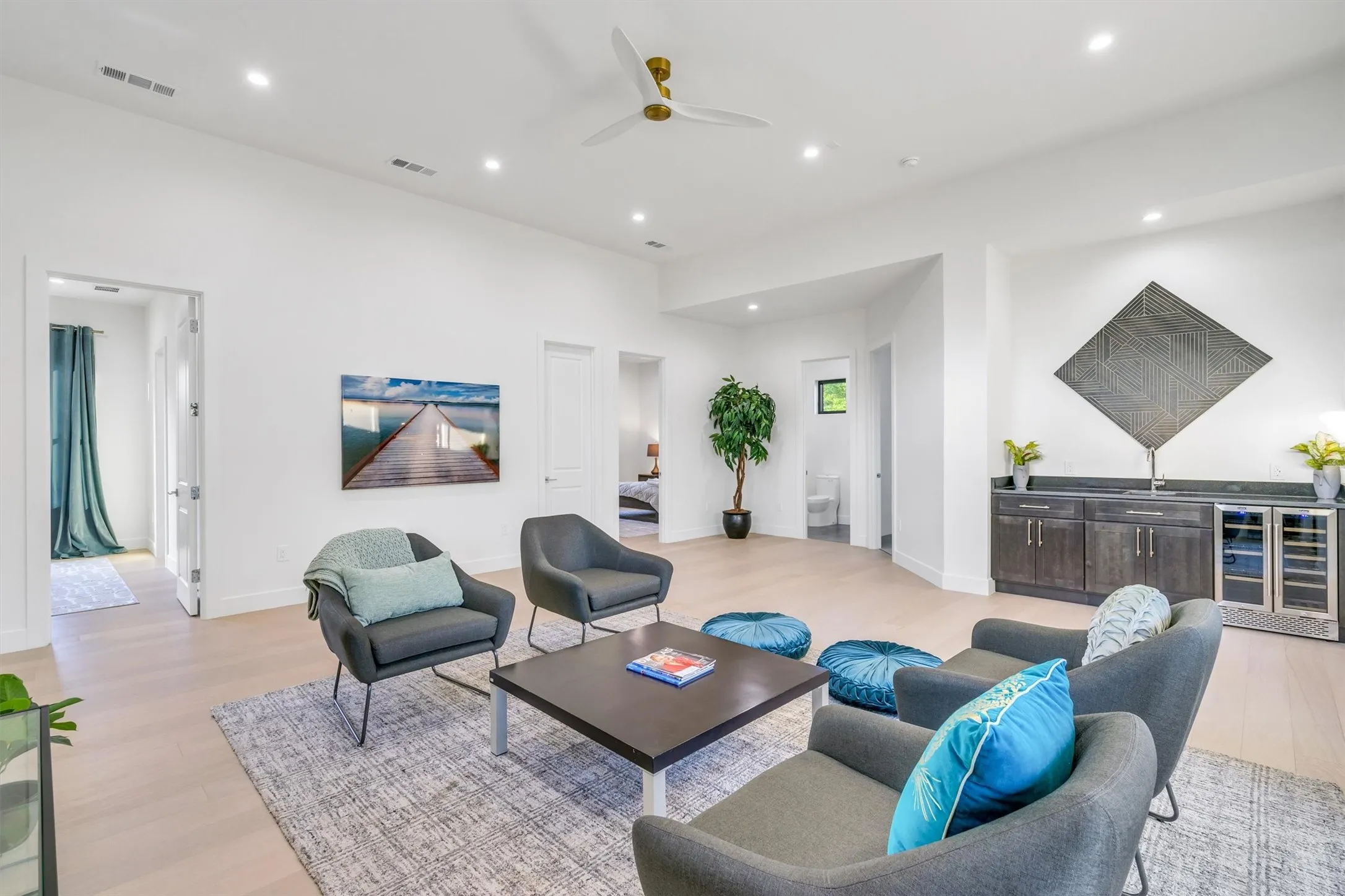 Living area with wine cooler, light wood-type flooring, a ceiling fan, recessed lighting, and bar with sink