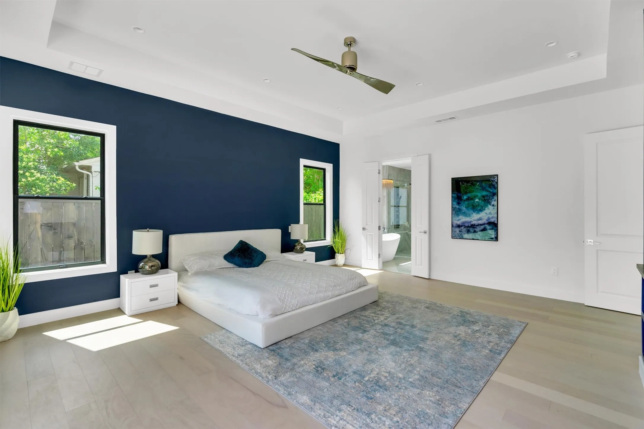 Bedroom featuring a tray ceiling, light wood-type flooring, ceiling fan, and recessed lighting