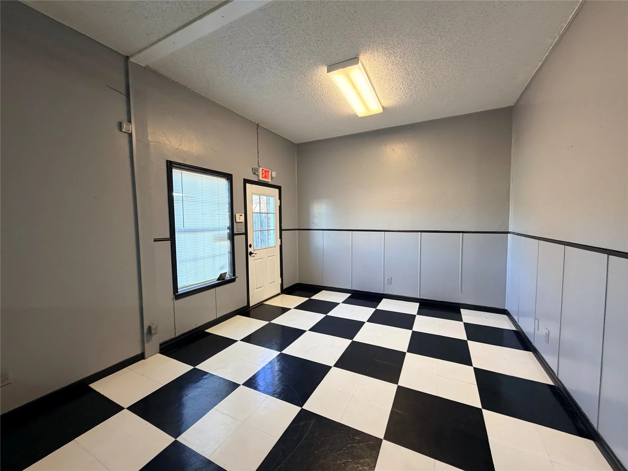Interior room with black-and-white checkered flooring, light walls, and a door with window panels