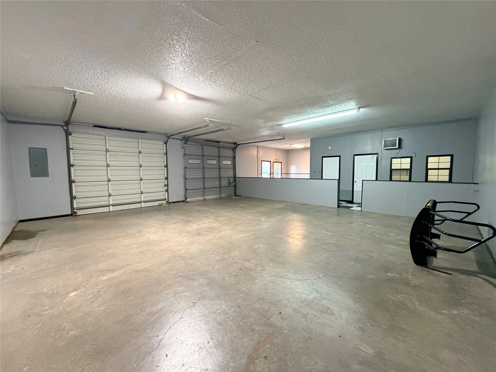 Garage bay with concrete flooring and a large overhead doors.