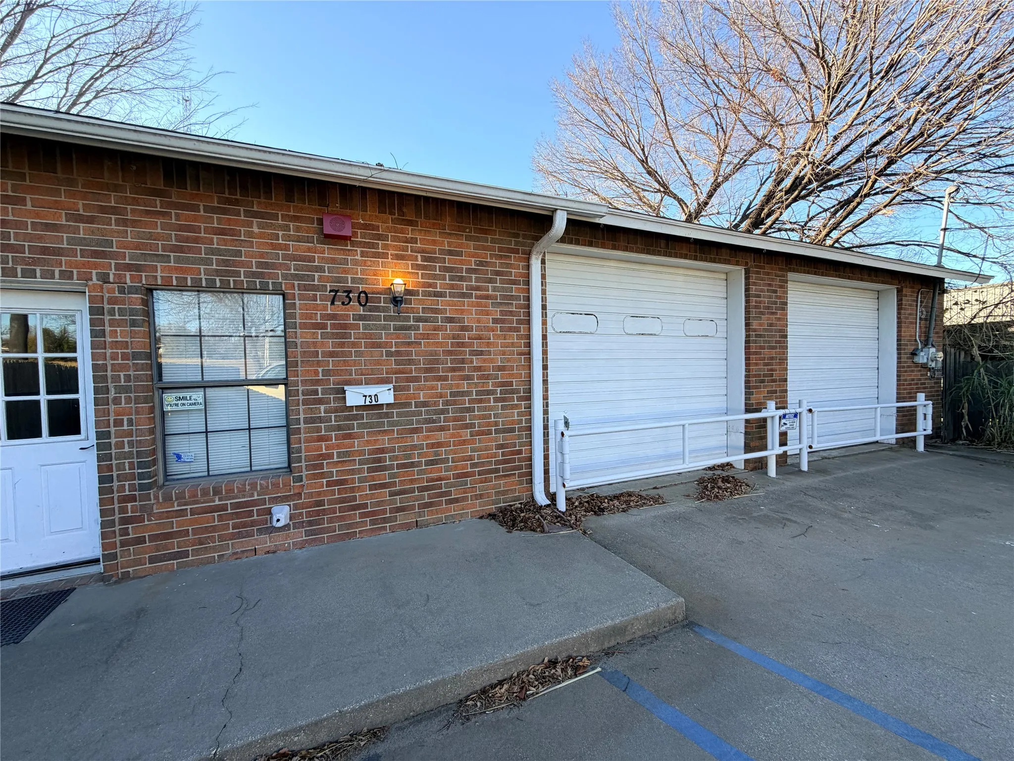Close-up of the brick garage section with two white overhead doors and a paved approach.