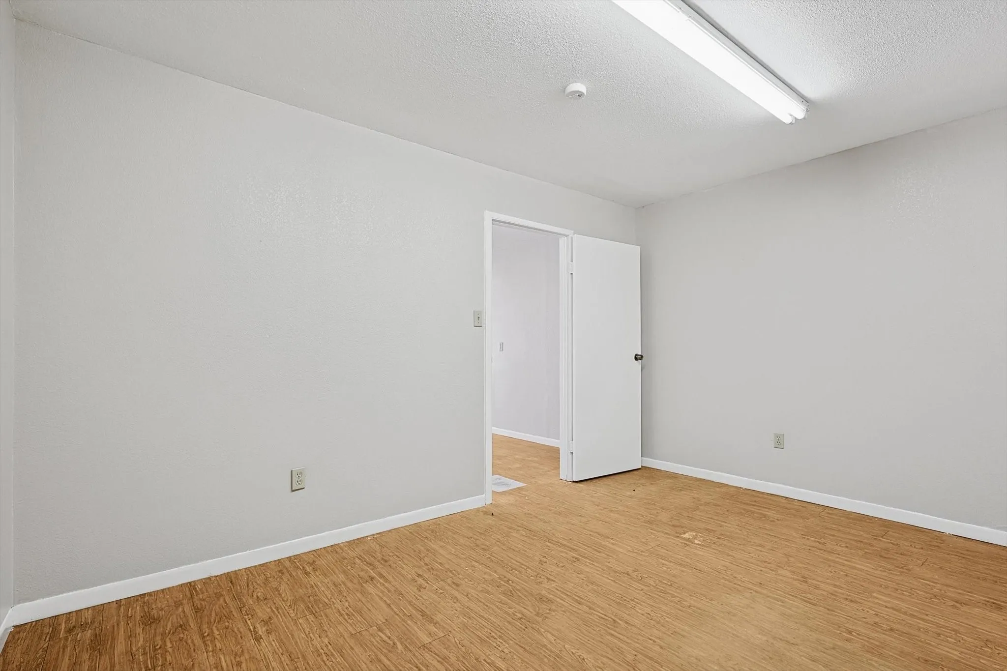 Unfurnished room featuring light hardwood / wood-style floors and a textured ceiling