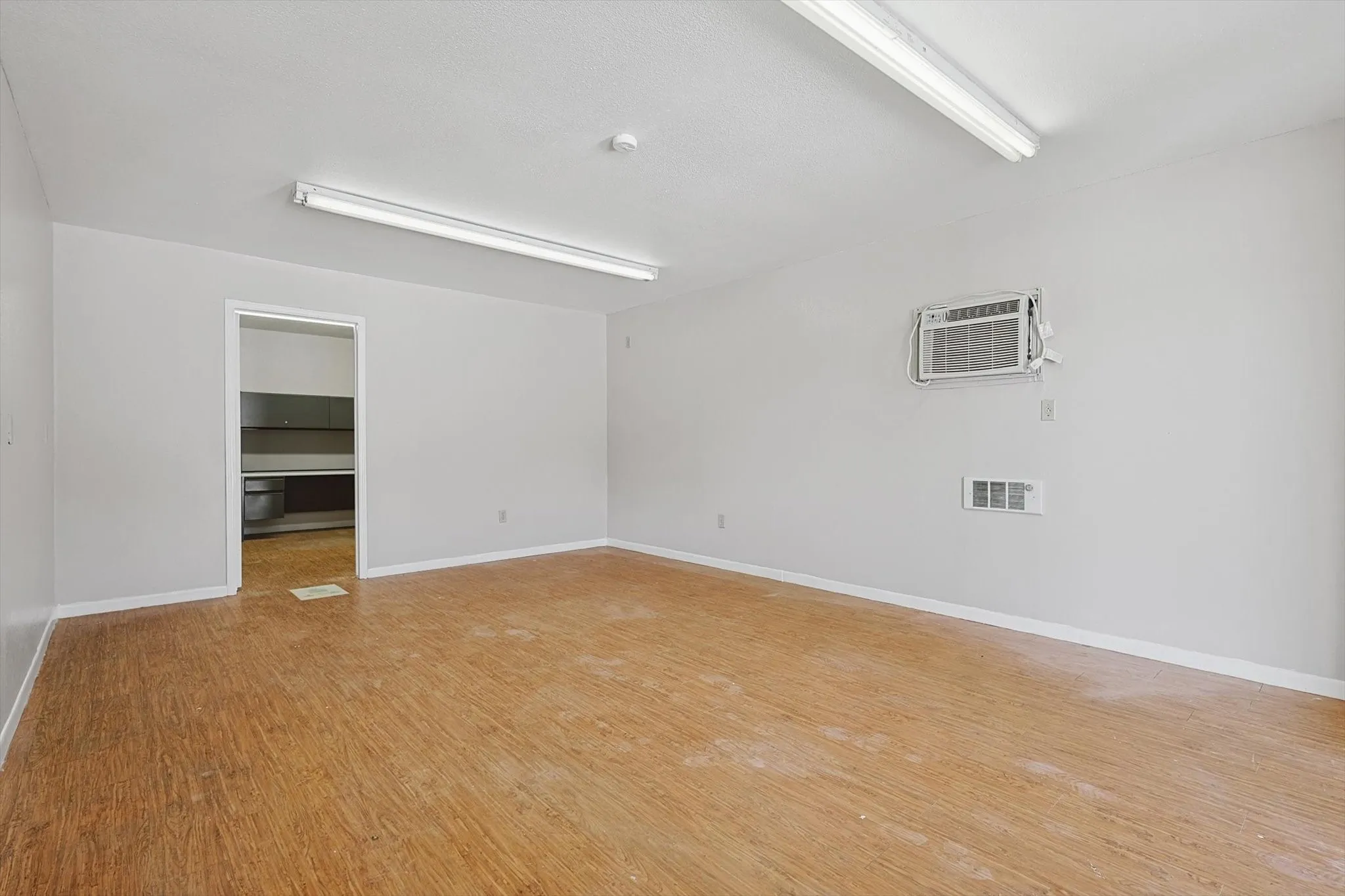 Unfurnished room with light hardwood / wood-style flooring and a wall unit AC