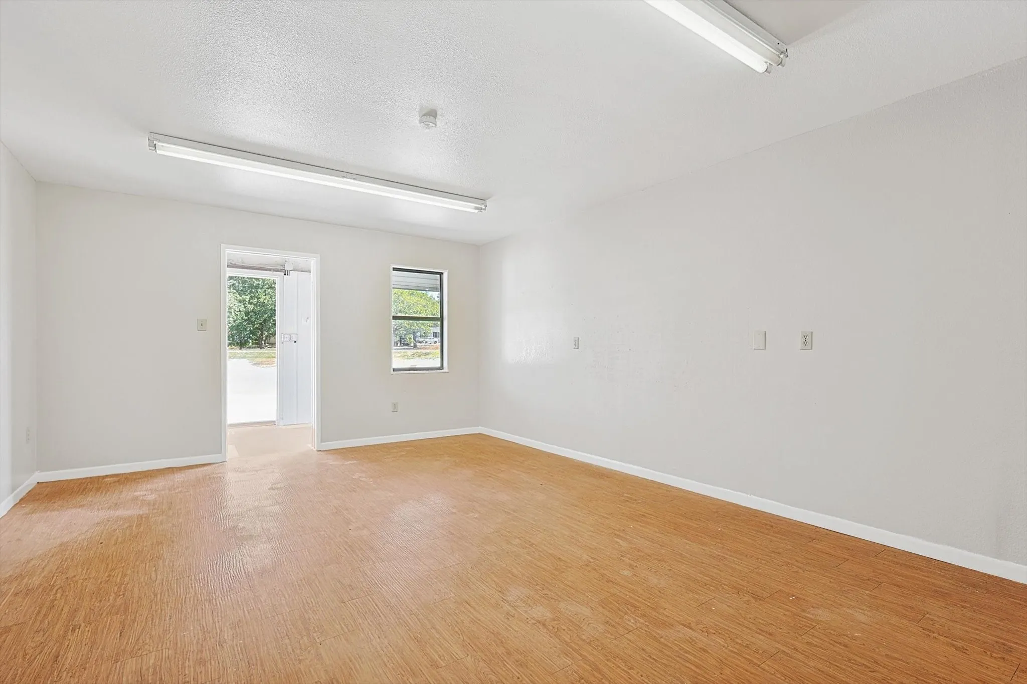 Empty room with a textured ceiling and light hardwood / wood-style floors
