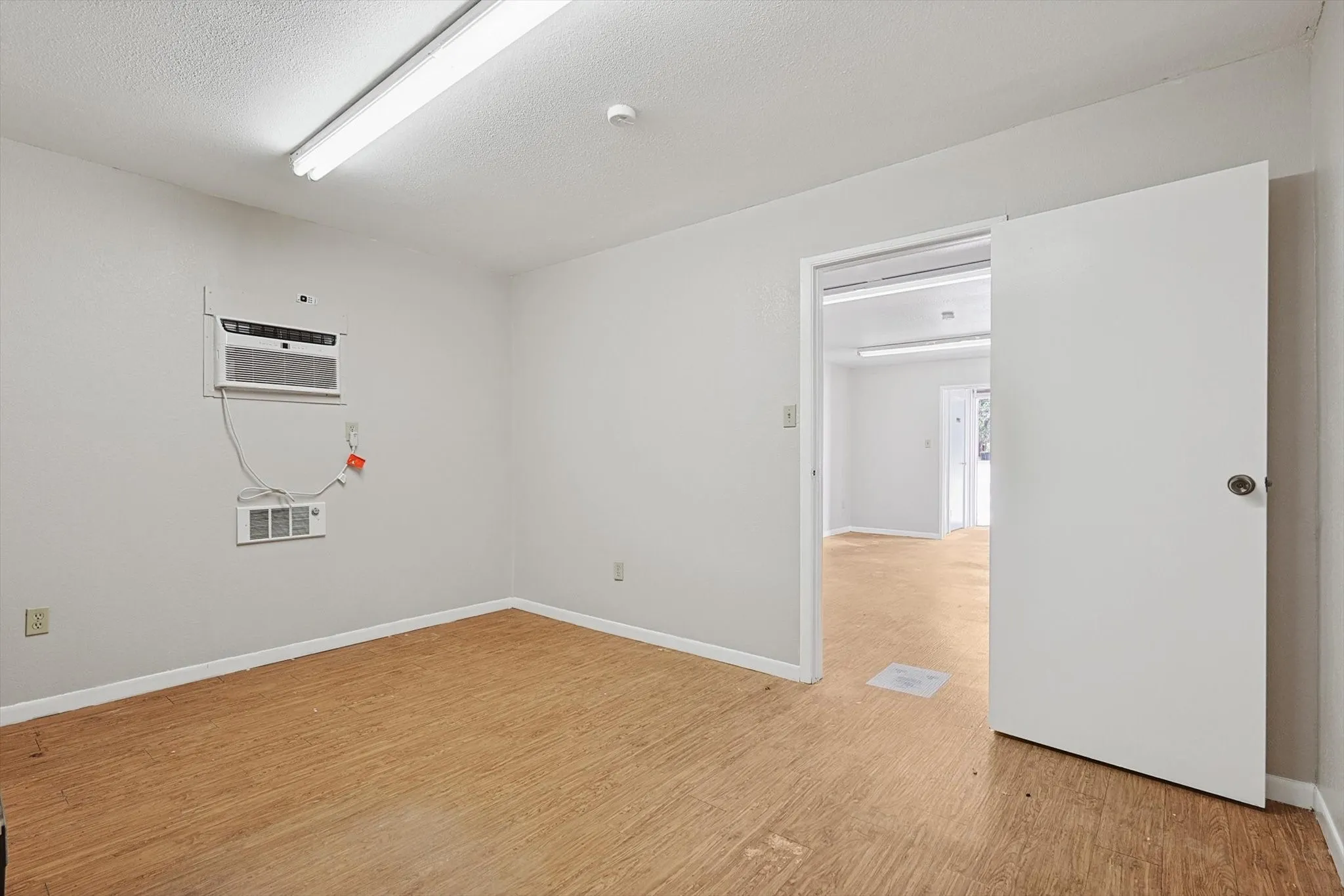 Spare room with light hardwood / wood-style floors, a textured ceiling, and a wall mounted air conditioner