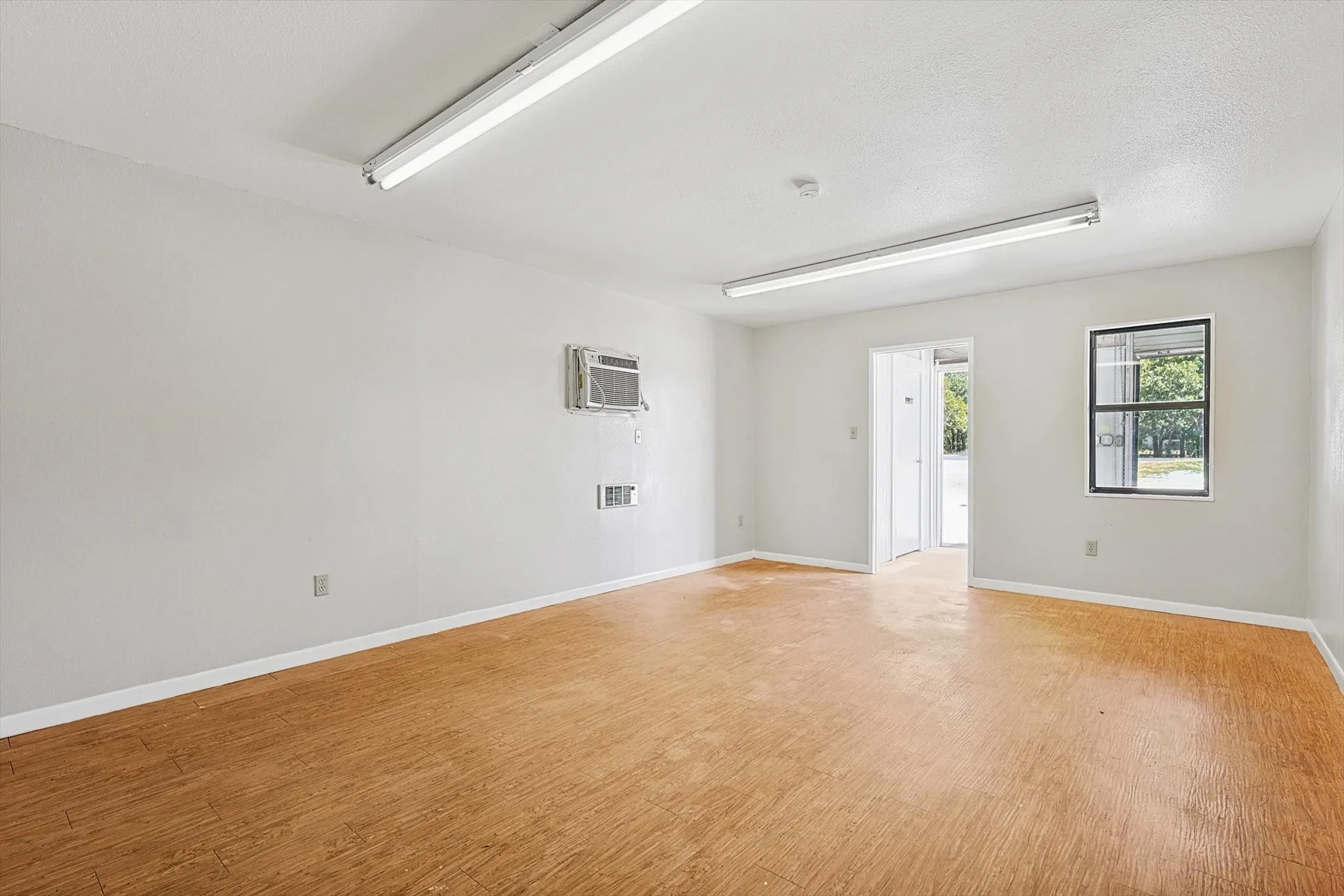 Unfurnished room with light hardwood / wood-style floors, a textured ceiling, and a wall mounted AC