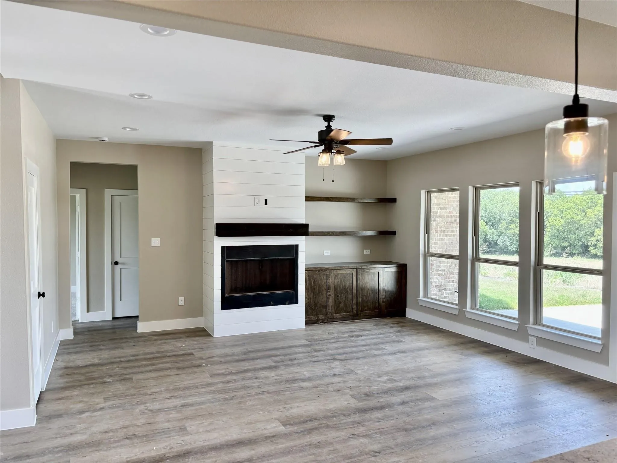 Unfurnished living room with light wood-type flooring, ceiling fan, and a fireplace