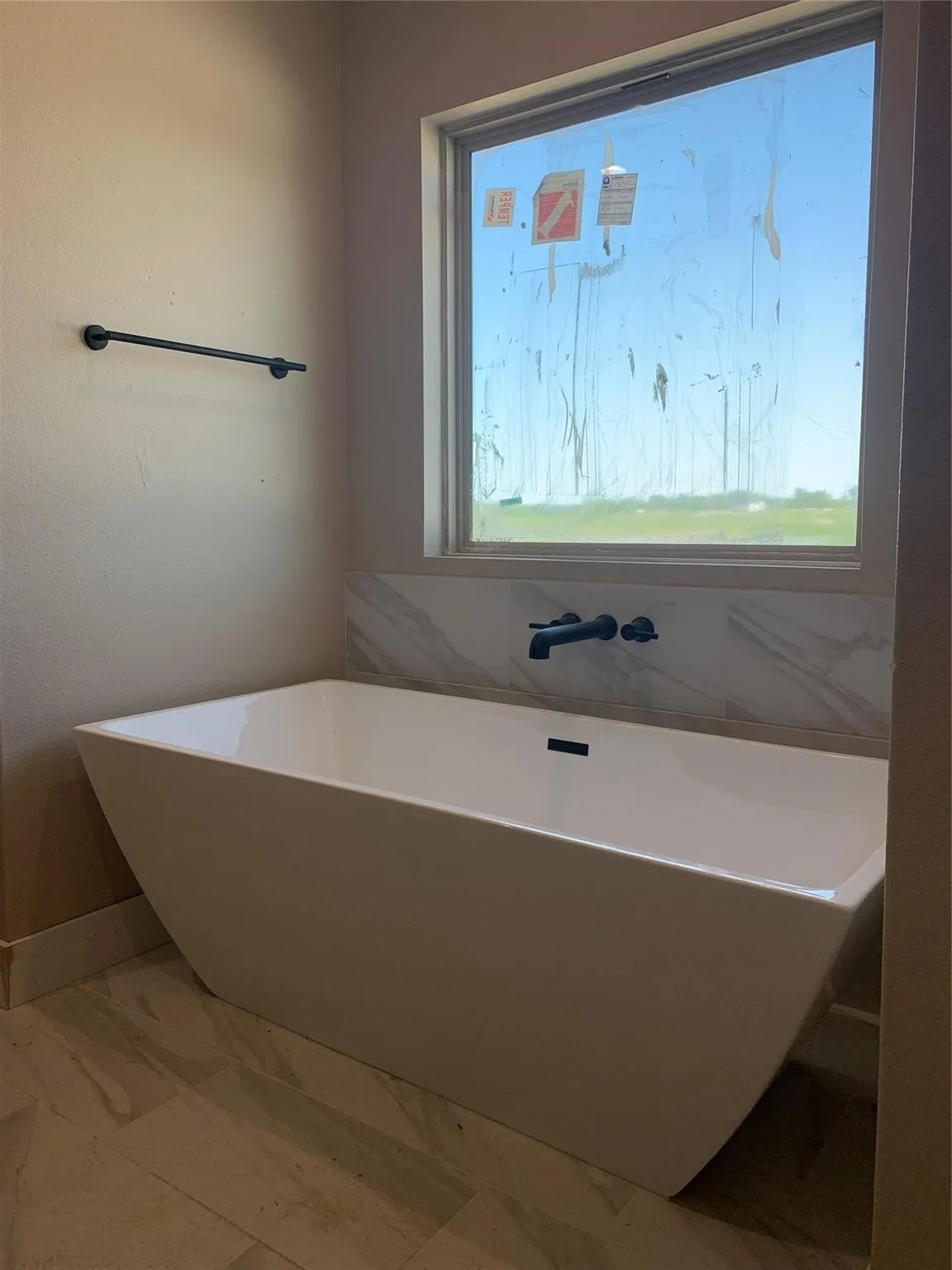 Bathroom with a freestanding bath and marble finish floors