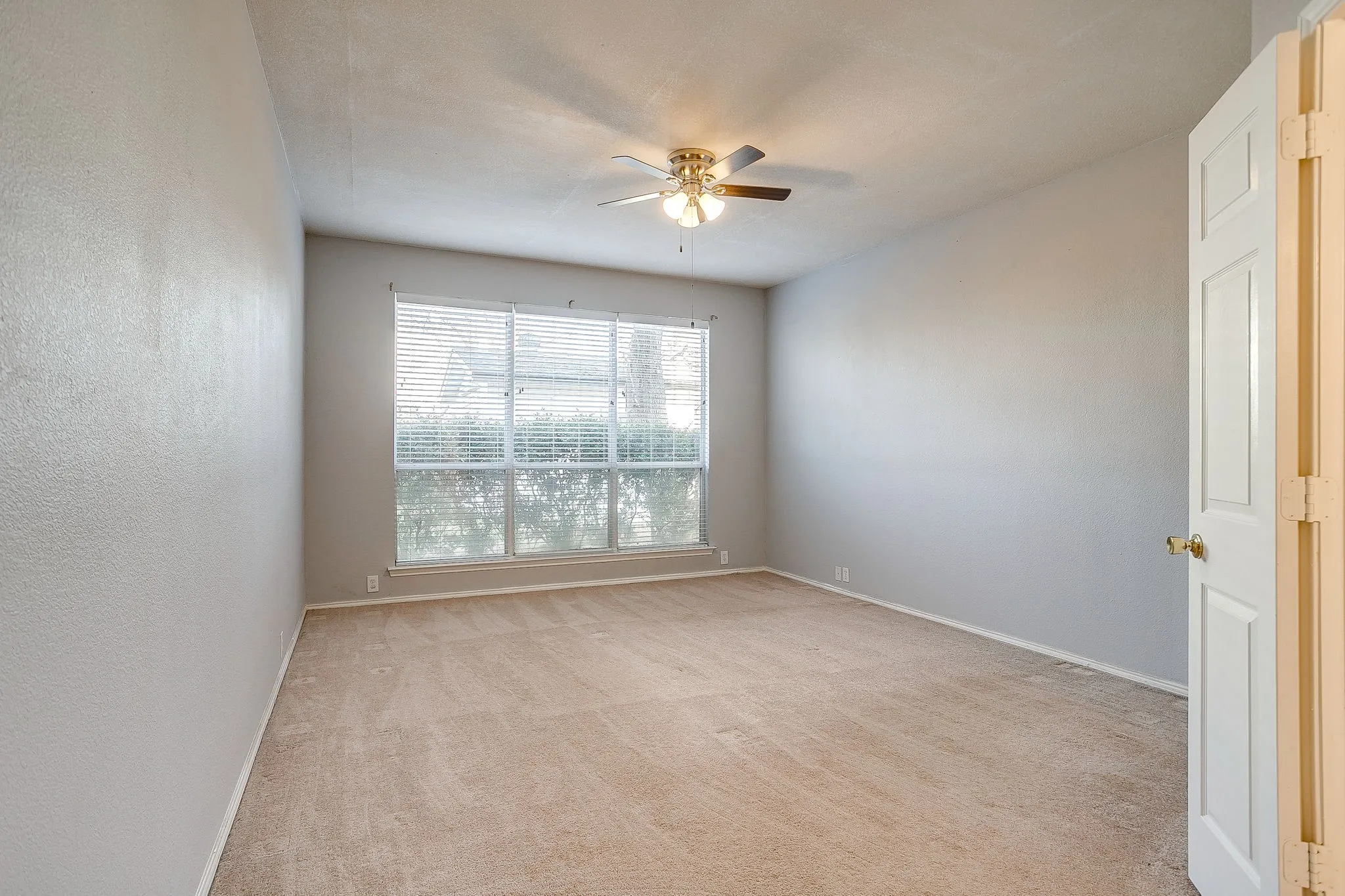 Empty room featuring light carpet and a ceiling fan