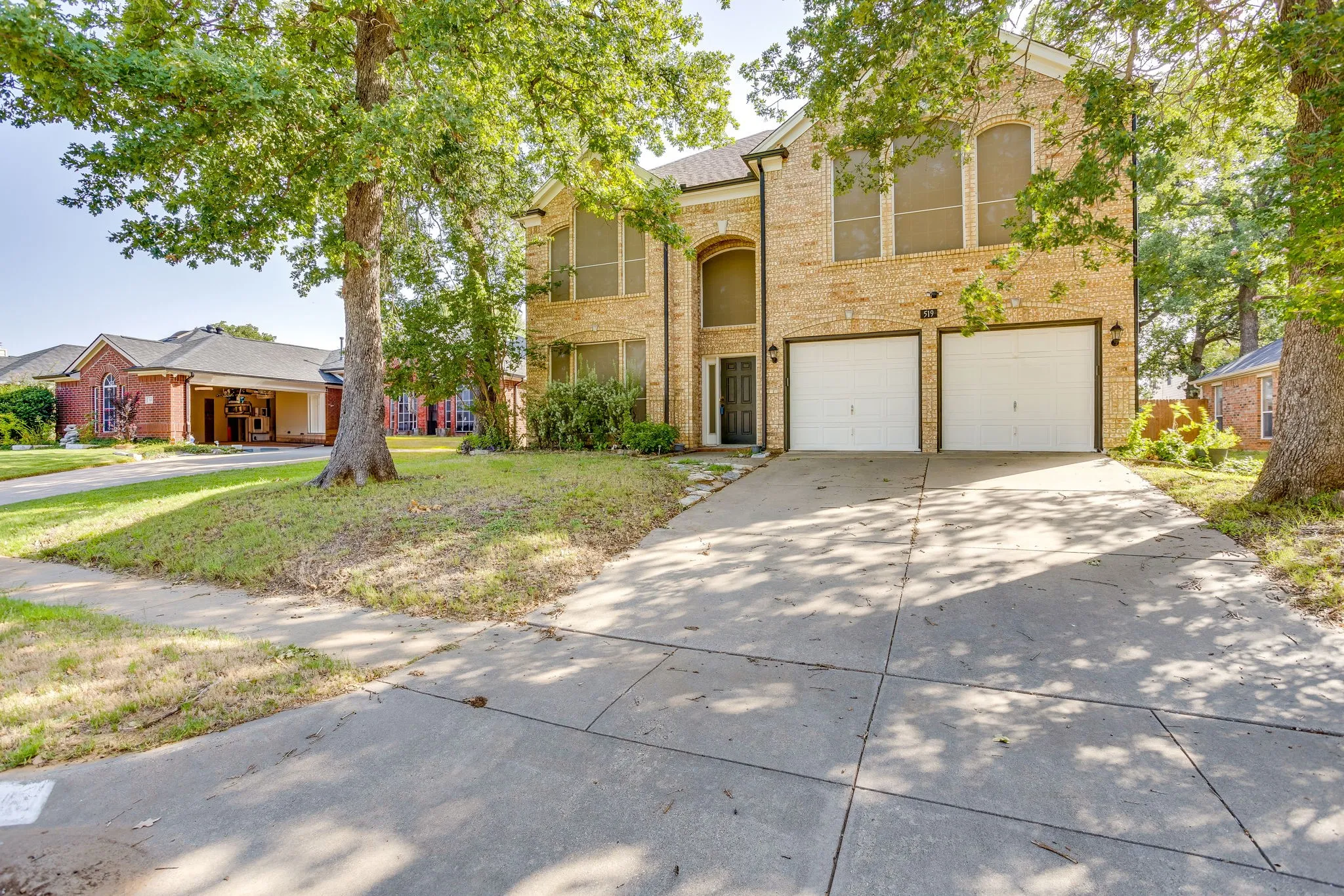 Two-story brick exterior with a prominent arched entry and a two-car garage
