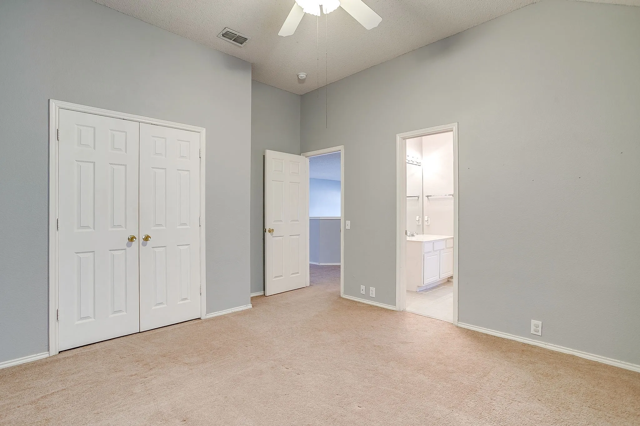 Unfurnished bedroom with a closet, light carpet, a ceiling fan, and ensuite bathroom