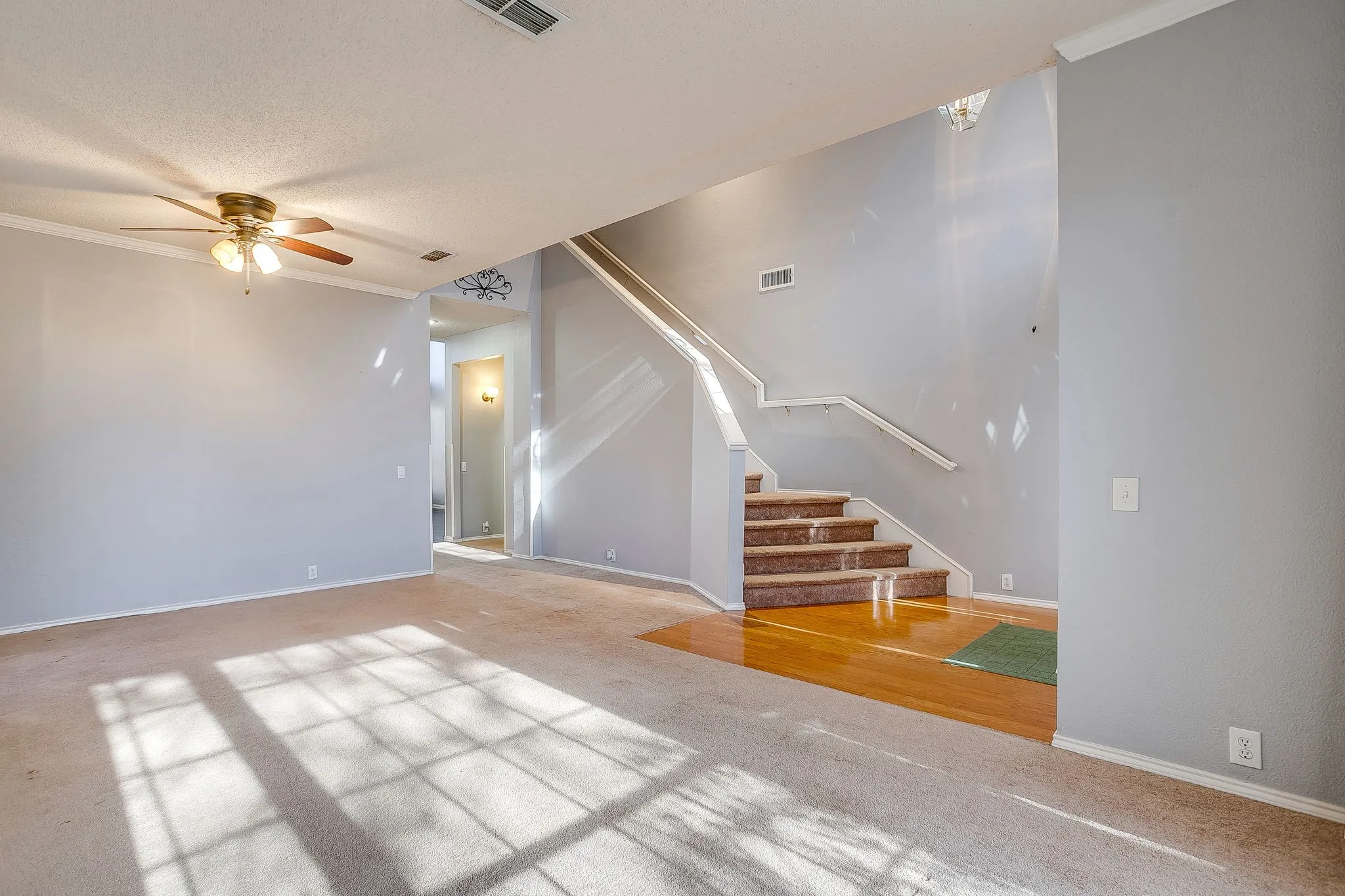 Unfurnished living room featuring a ceiling fan, ornamental molding, and carpet floors