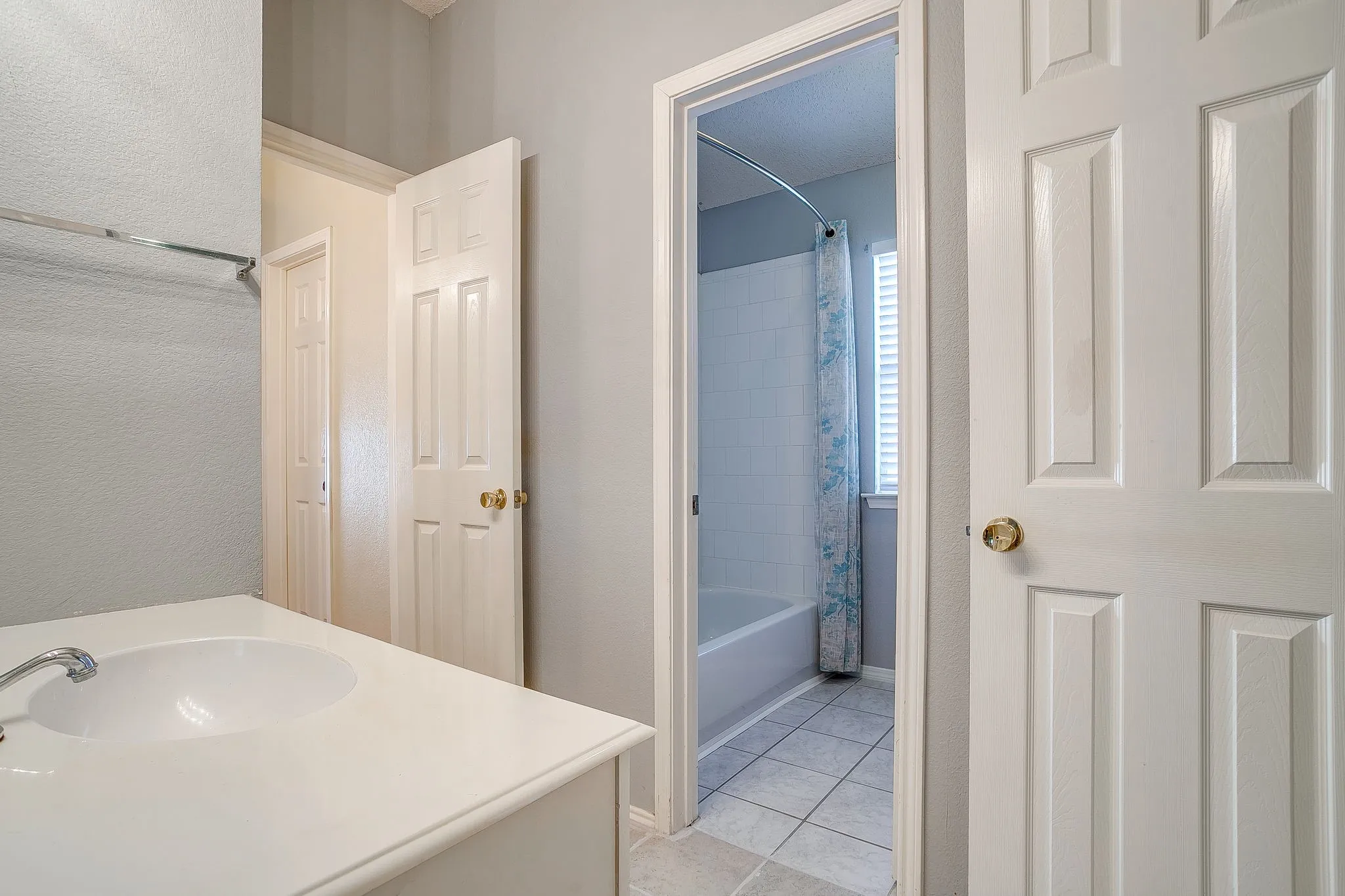 Full bath with shower / bathtub combination with curtain, vanity, a textured wall, and light tile patterned flooring