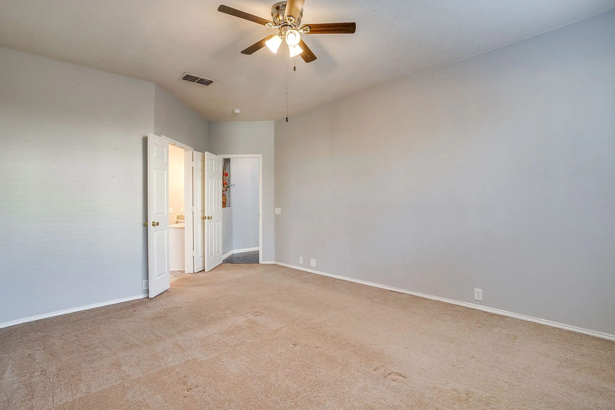 Empty room with a ceiling fan and light carpet