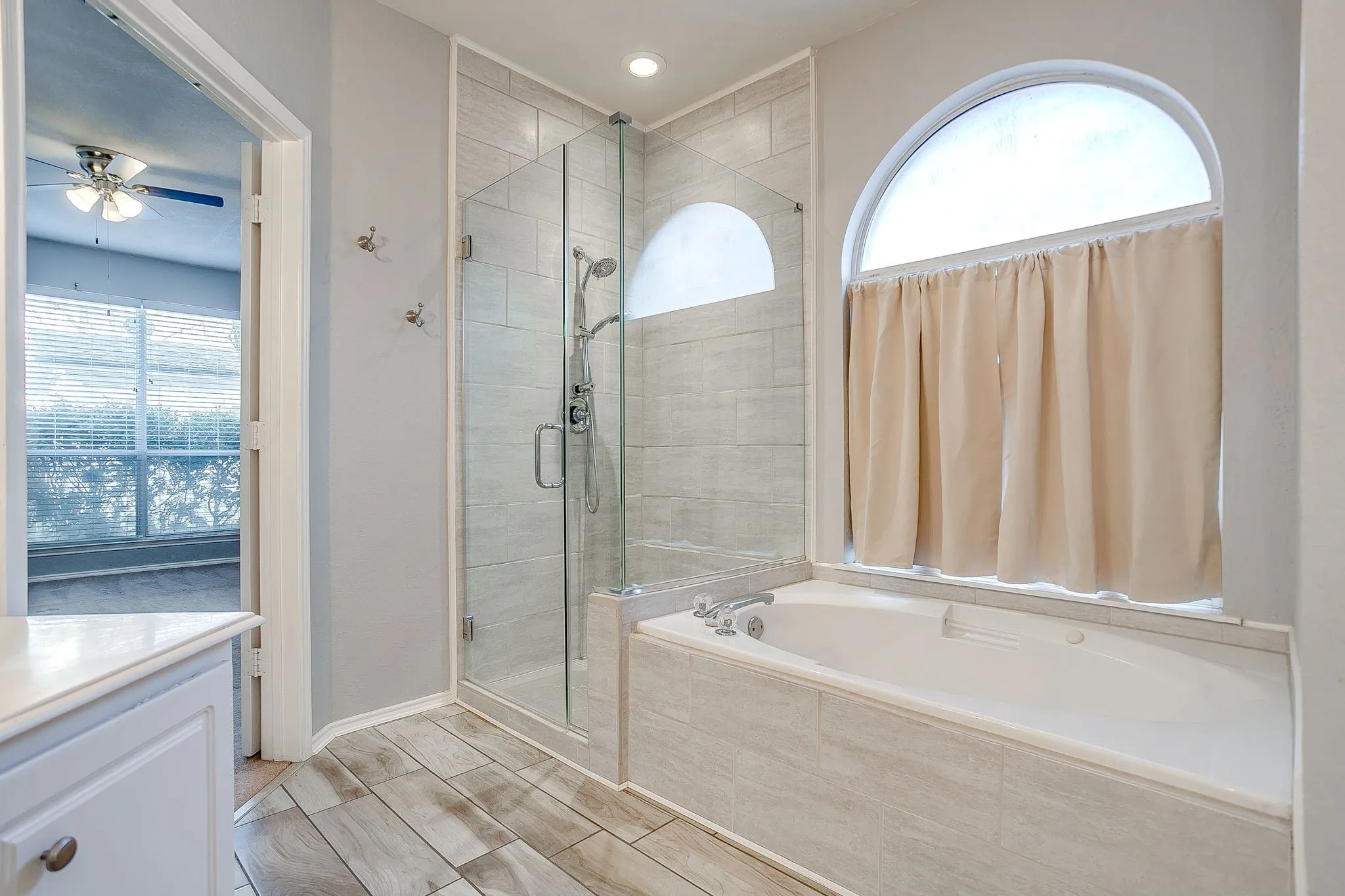 Bathroom with plenty of natural light, ceiling fan, a garden tub, and a shower stall