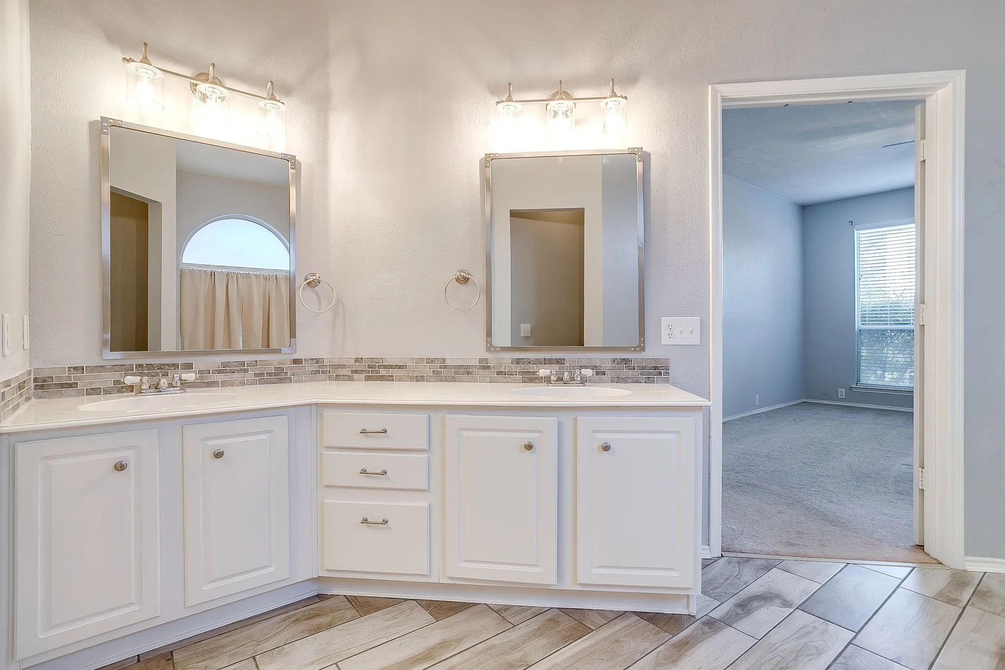 Bathroom with double vanity, light carpet, and healthy amount of natural light