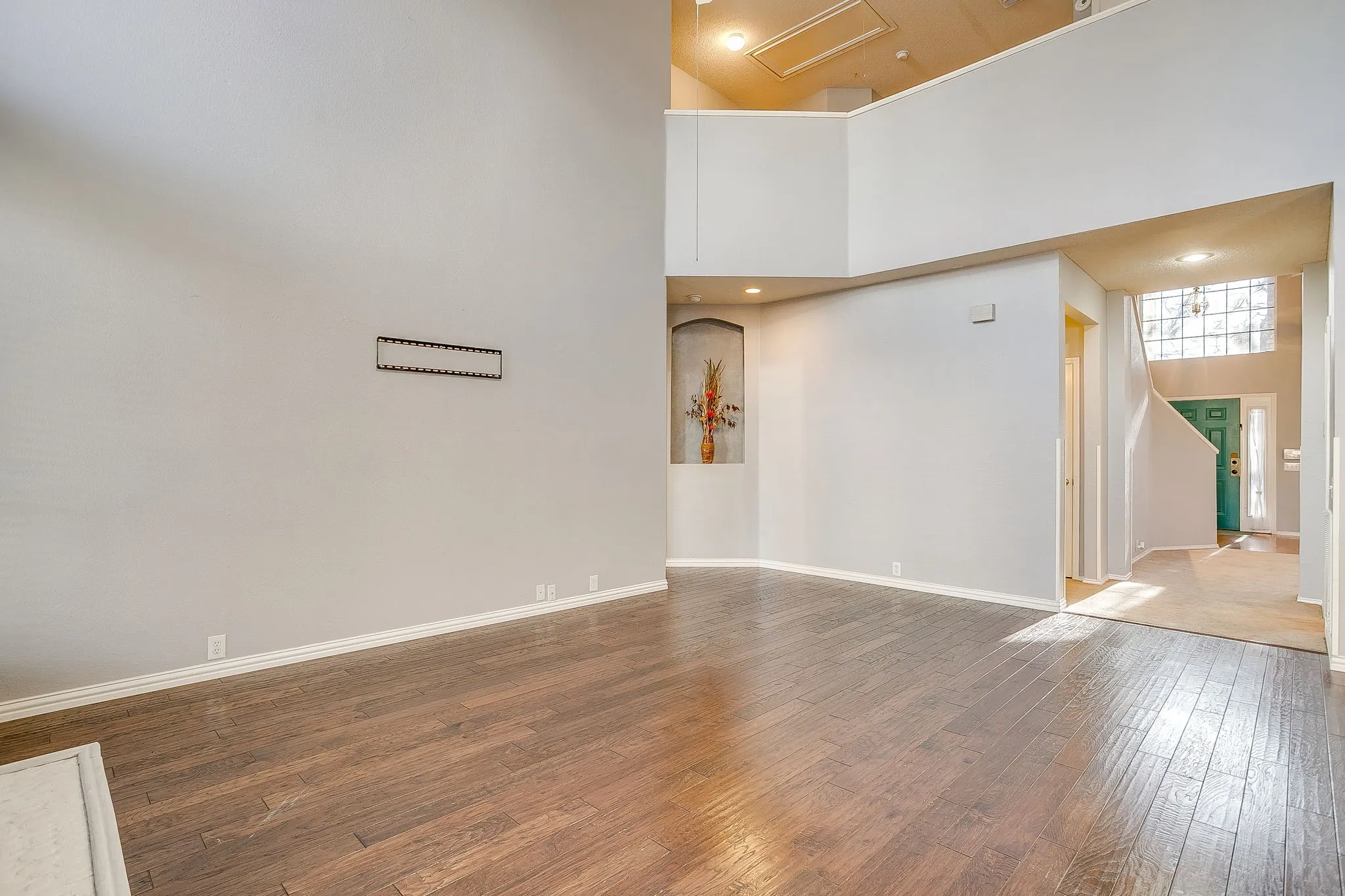 Empty room featuring a high ceiling, hardwood / wood-style flooring, and recessed lighting