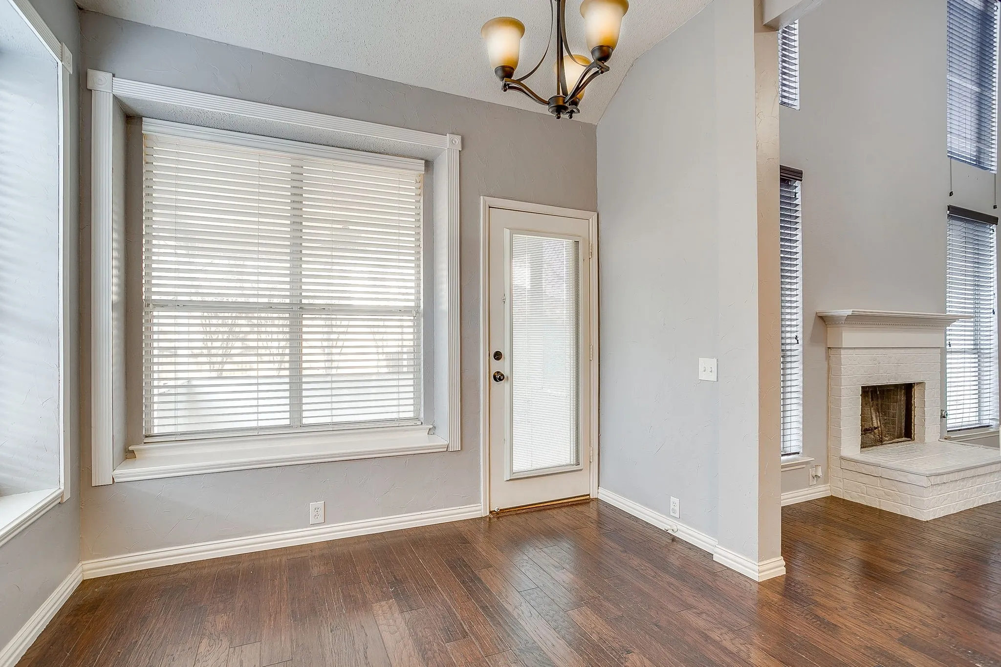 Entryway featuring hanging lights, dark wood-style floors, a fireplace, and lofted ceiling