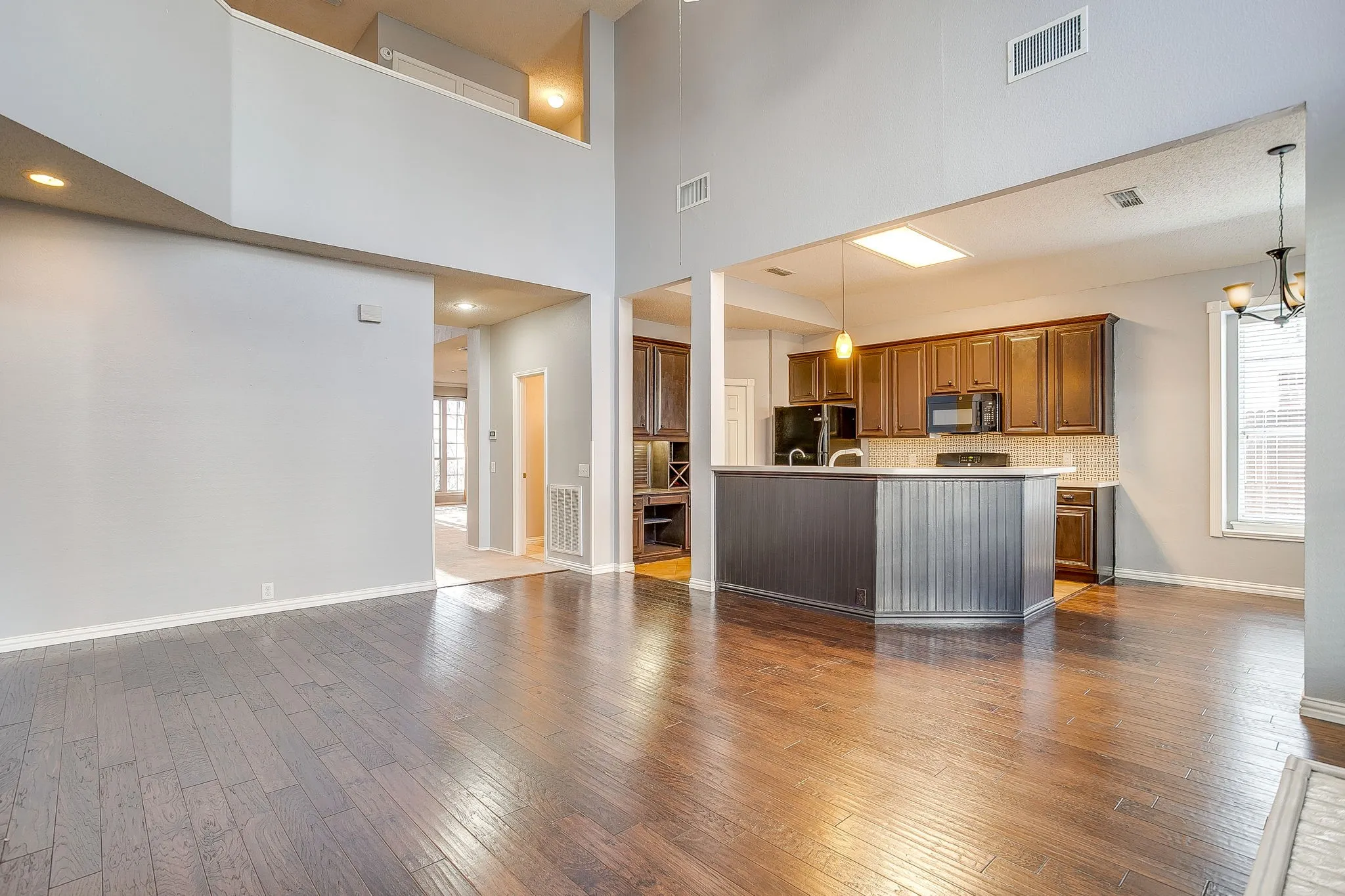 Living room with dark wood-type flooring, a chandelier, and a high ceiling