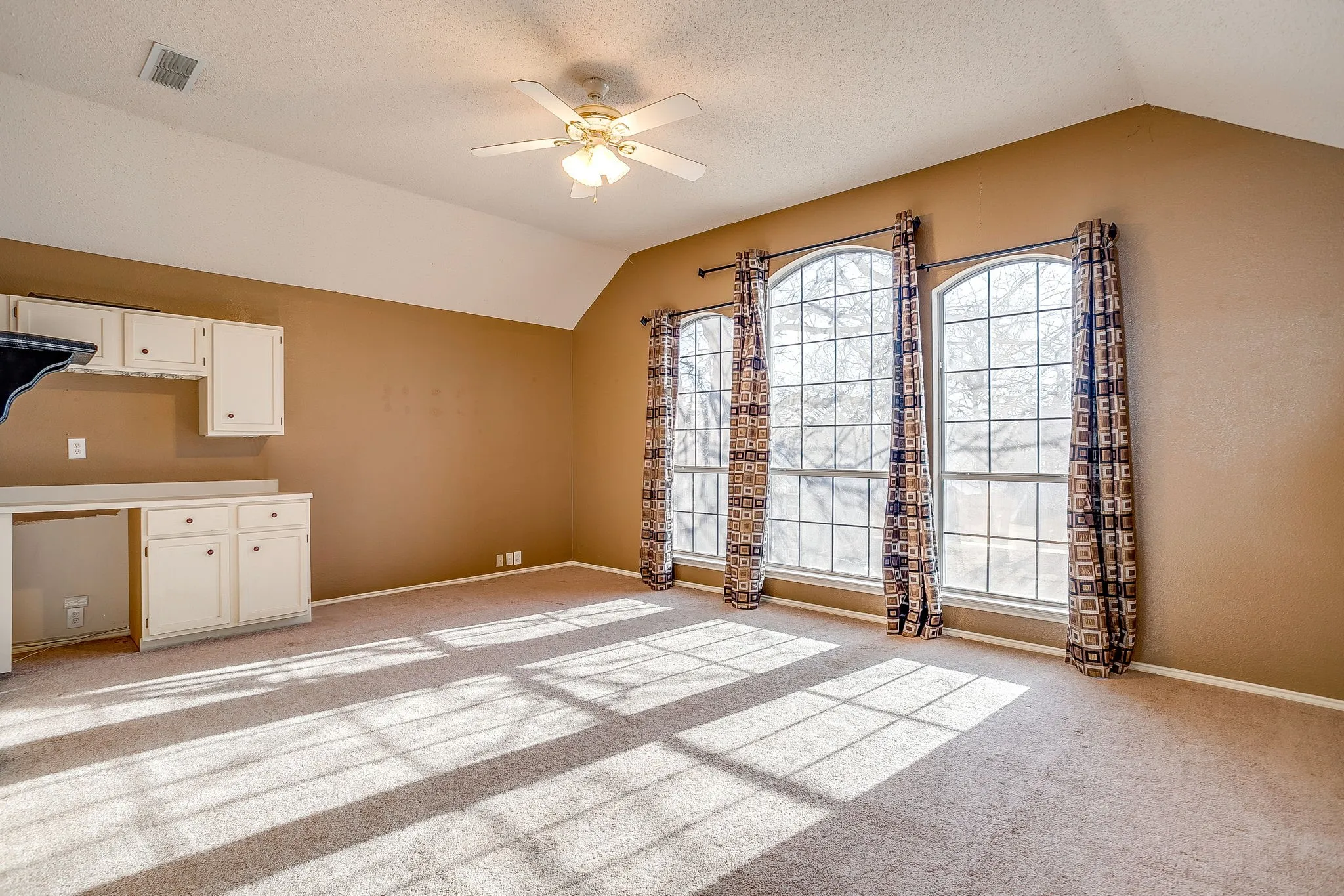 Unfurnished dining area with ceiling fan, light carpet, and a textured ceiling