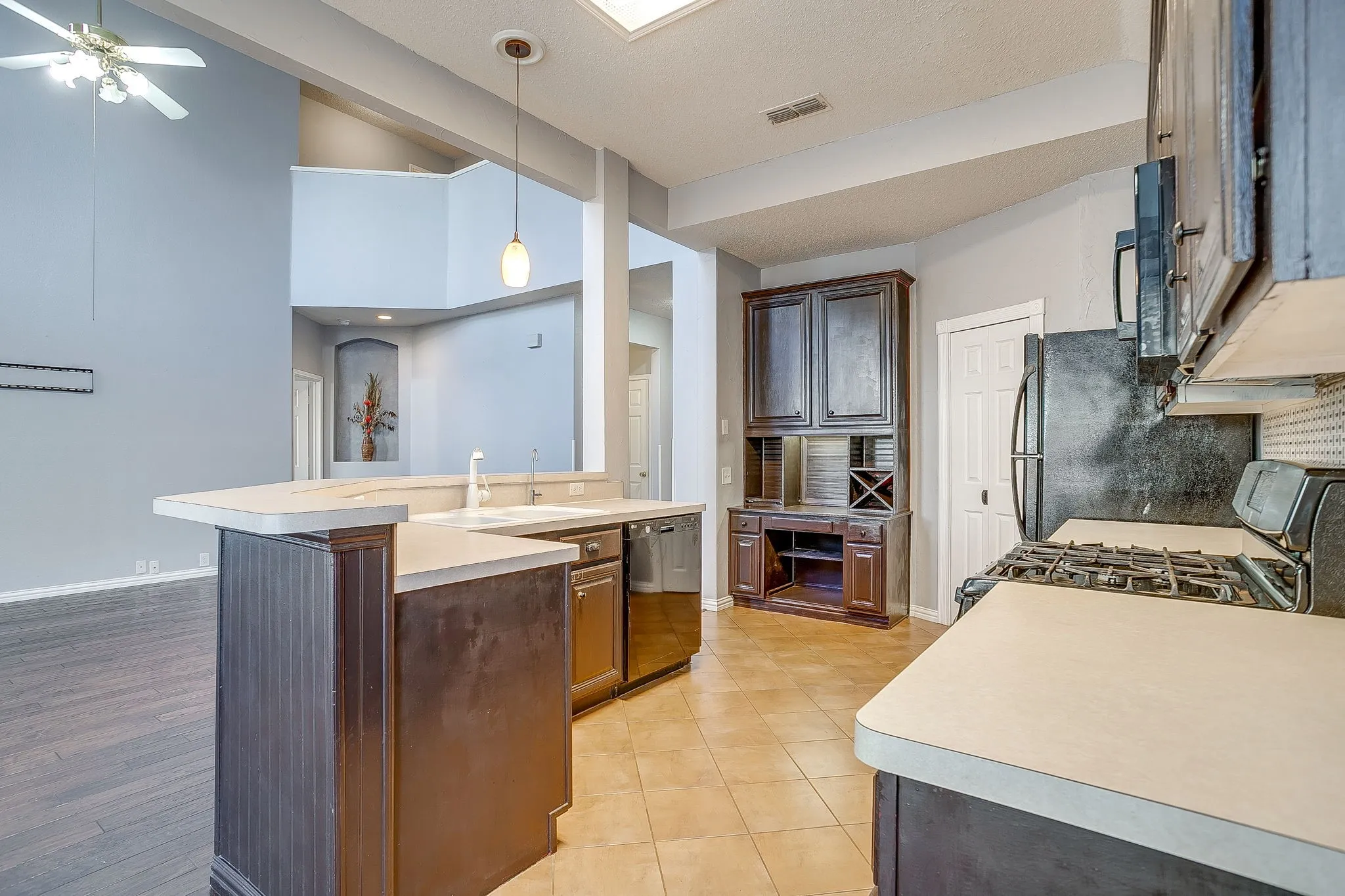 Kitchen with backsplash, light countertops, black appliances, pendant lighting, and a high ceiling