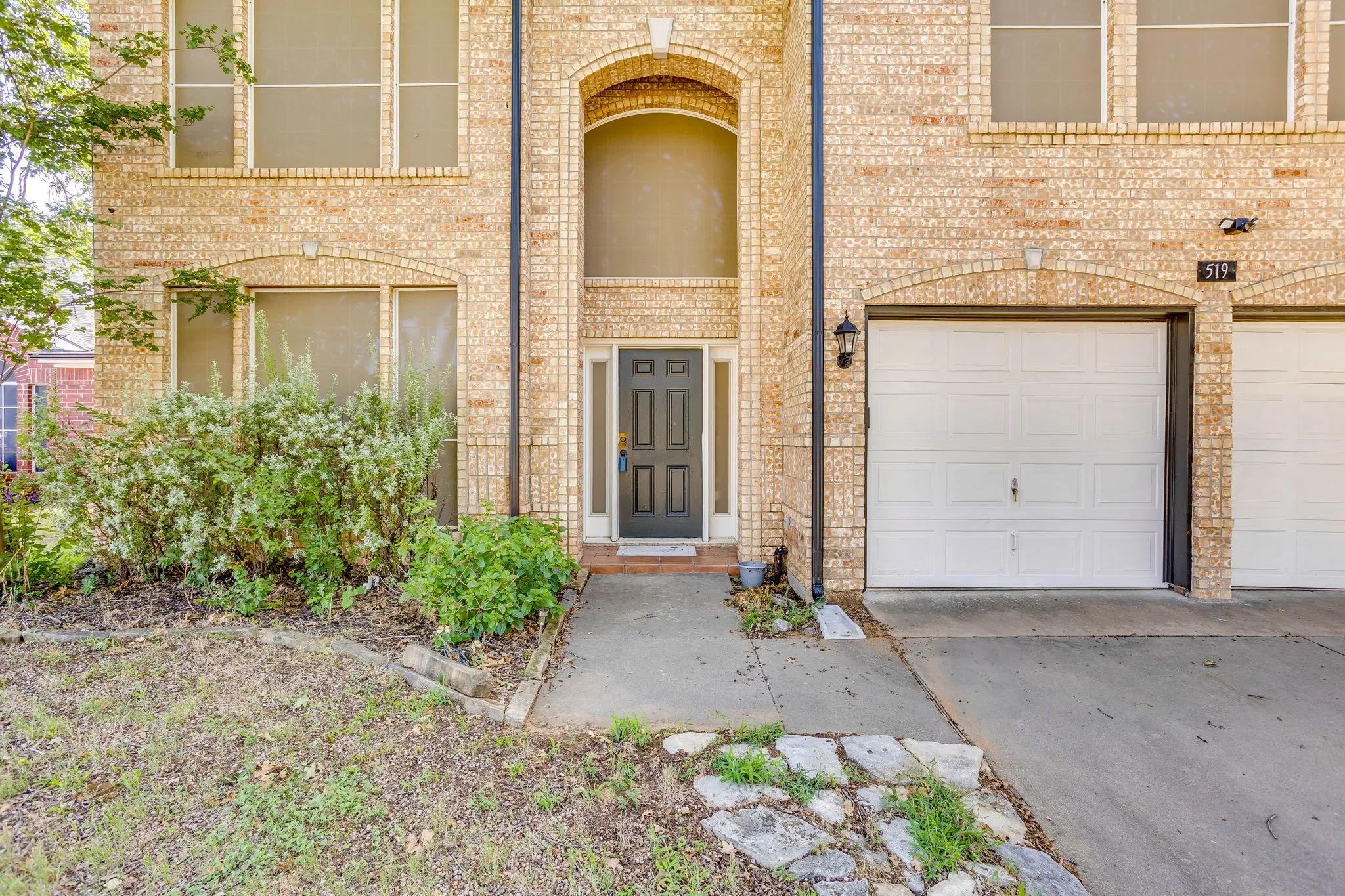 Brick-clad exterior featuring a prominent arched entryway and a dark-paneled front door