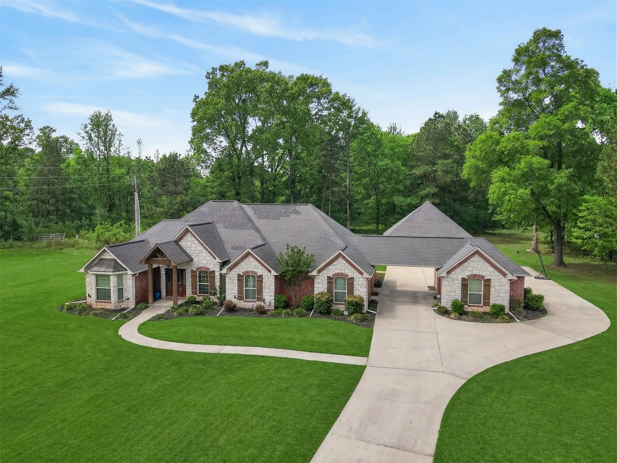 View of front of house featuring a front yard, driveway, stone siding, and roof with shingles