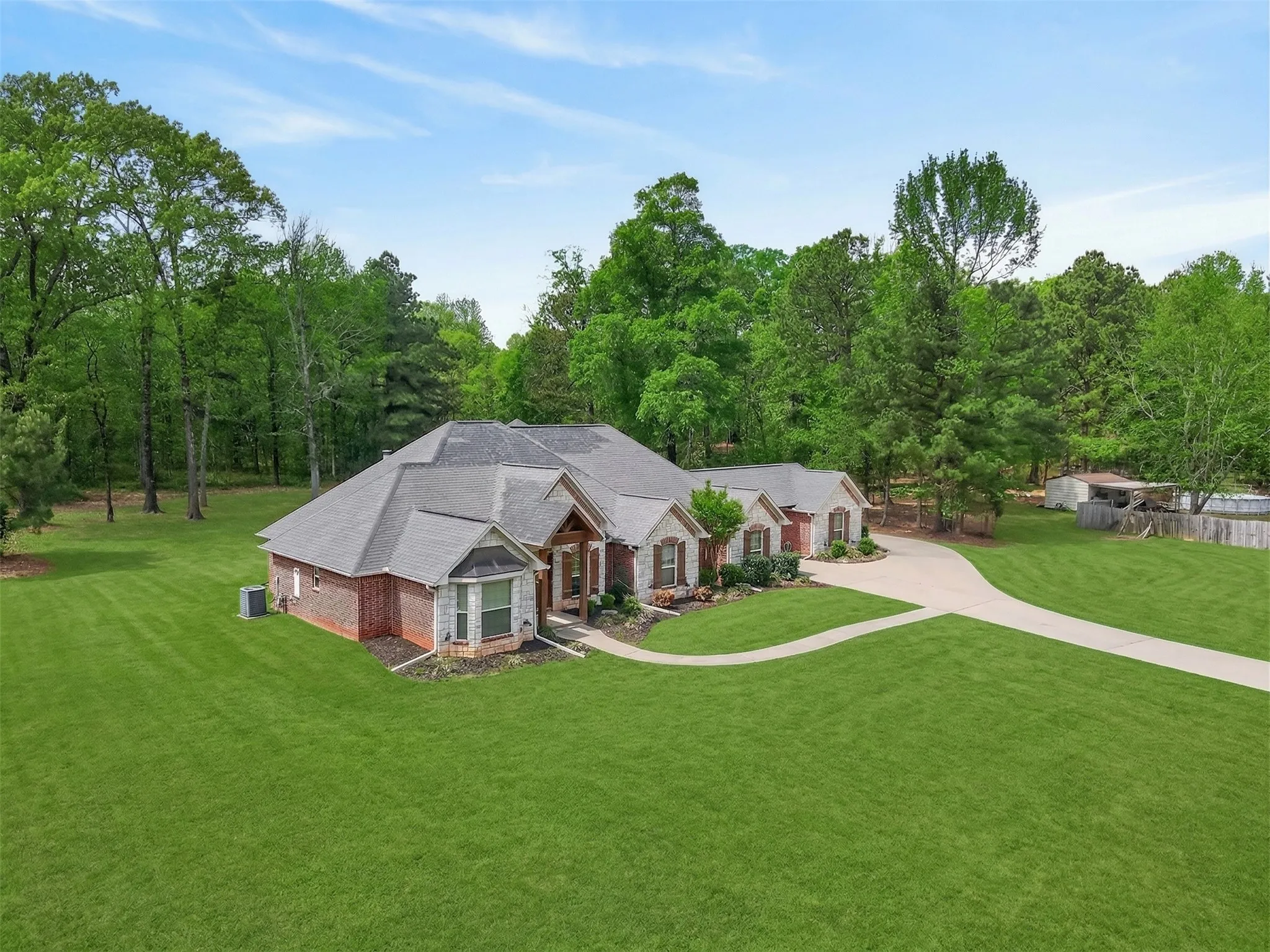 View of front of home featuring a front lawn, brick siding, view of wooded area, and a porch