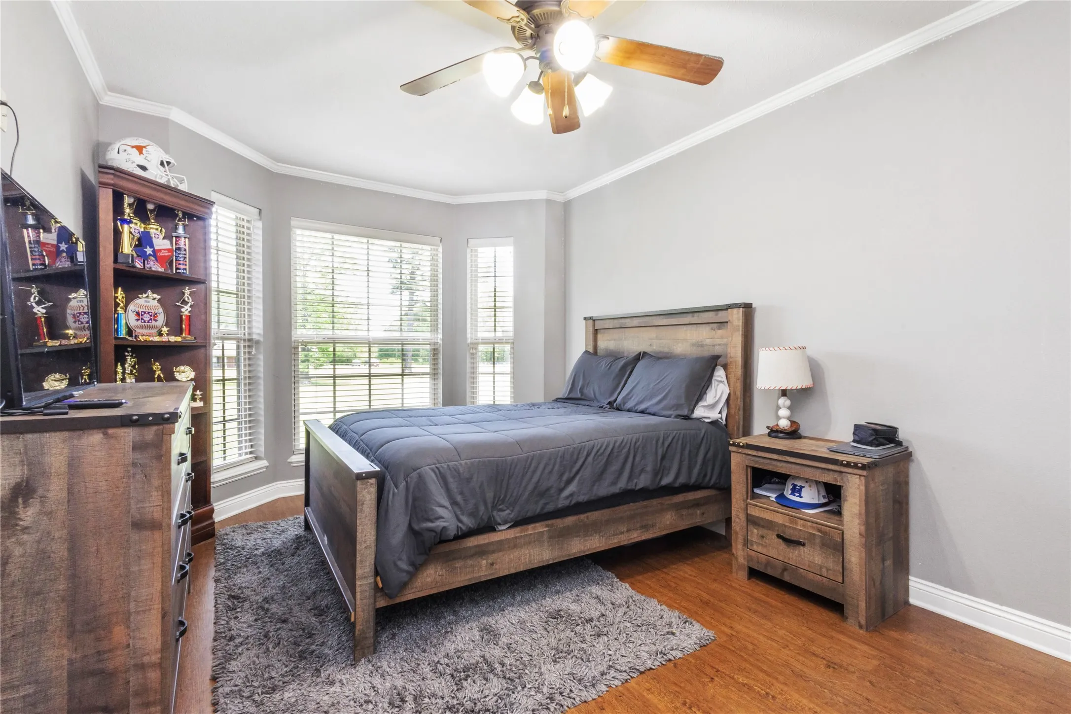 Bedroom featuring dark wood-style flooring, crown molding, and a ceiling fan