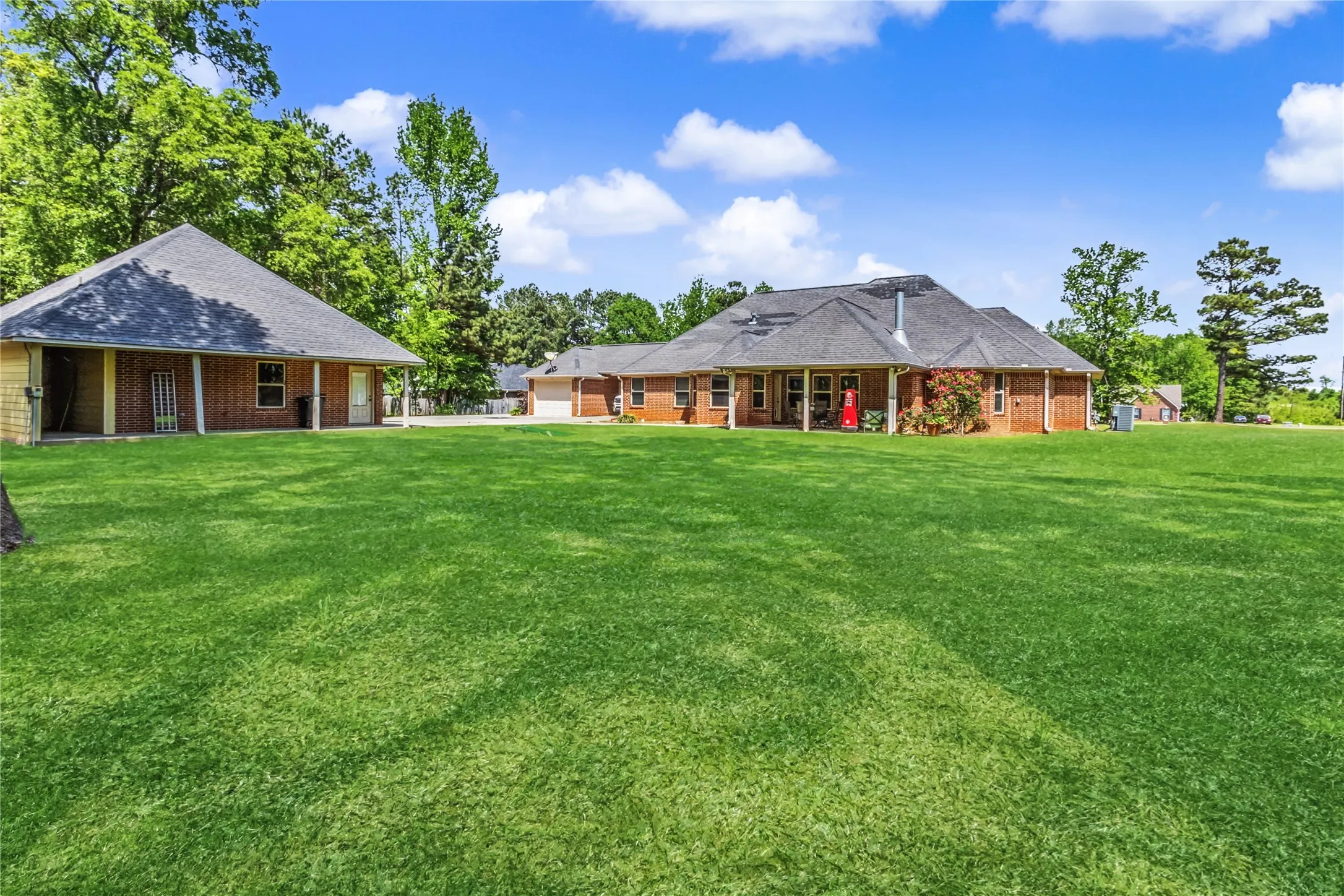 Rear view of property with a yard, brick siding, a patio, a shingled roof, and a garage