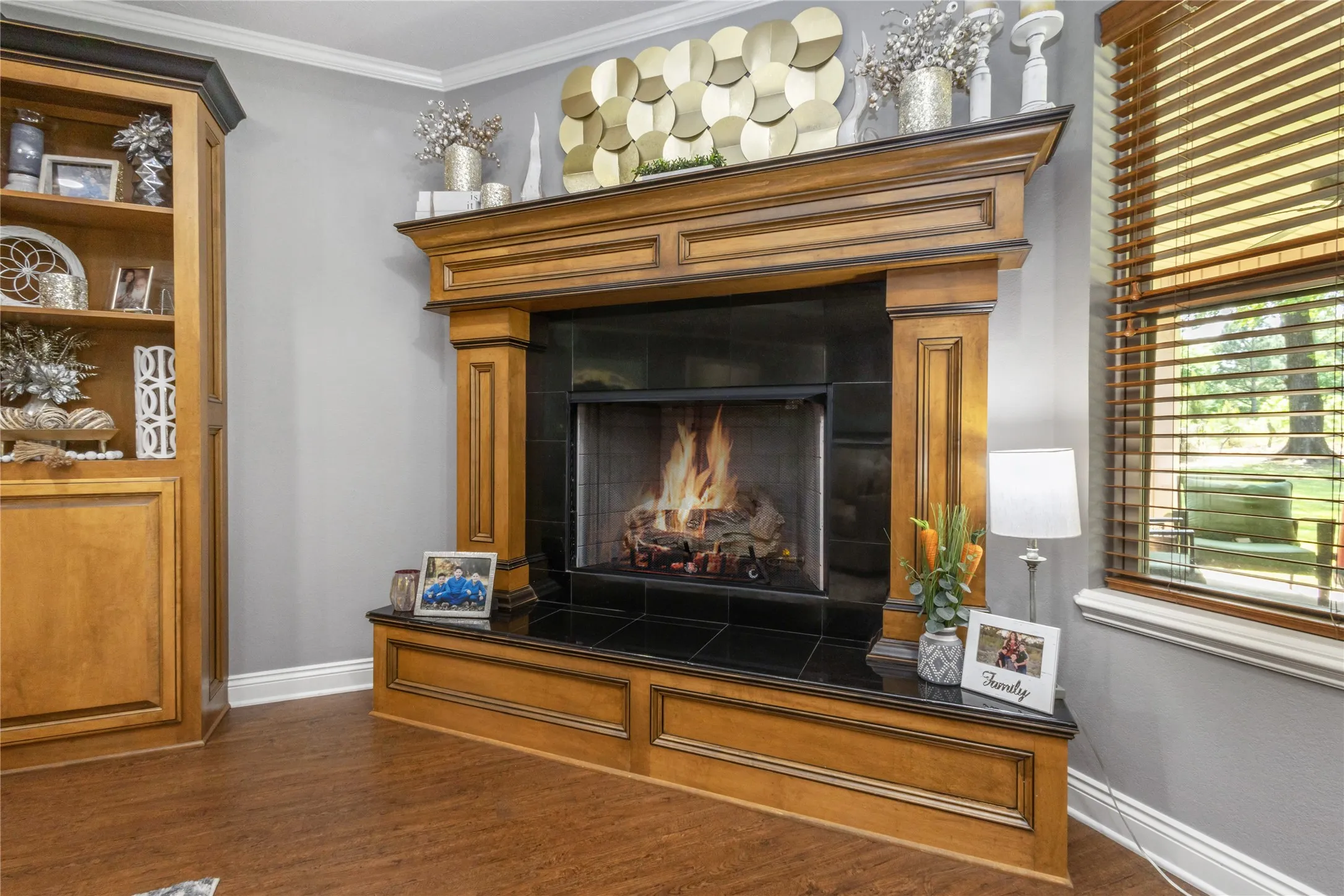 Detailed view of a tile fireplace, wood finished floors, and crown molding